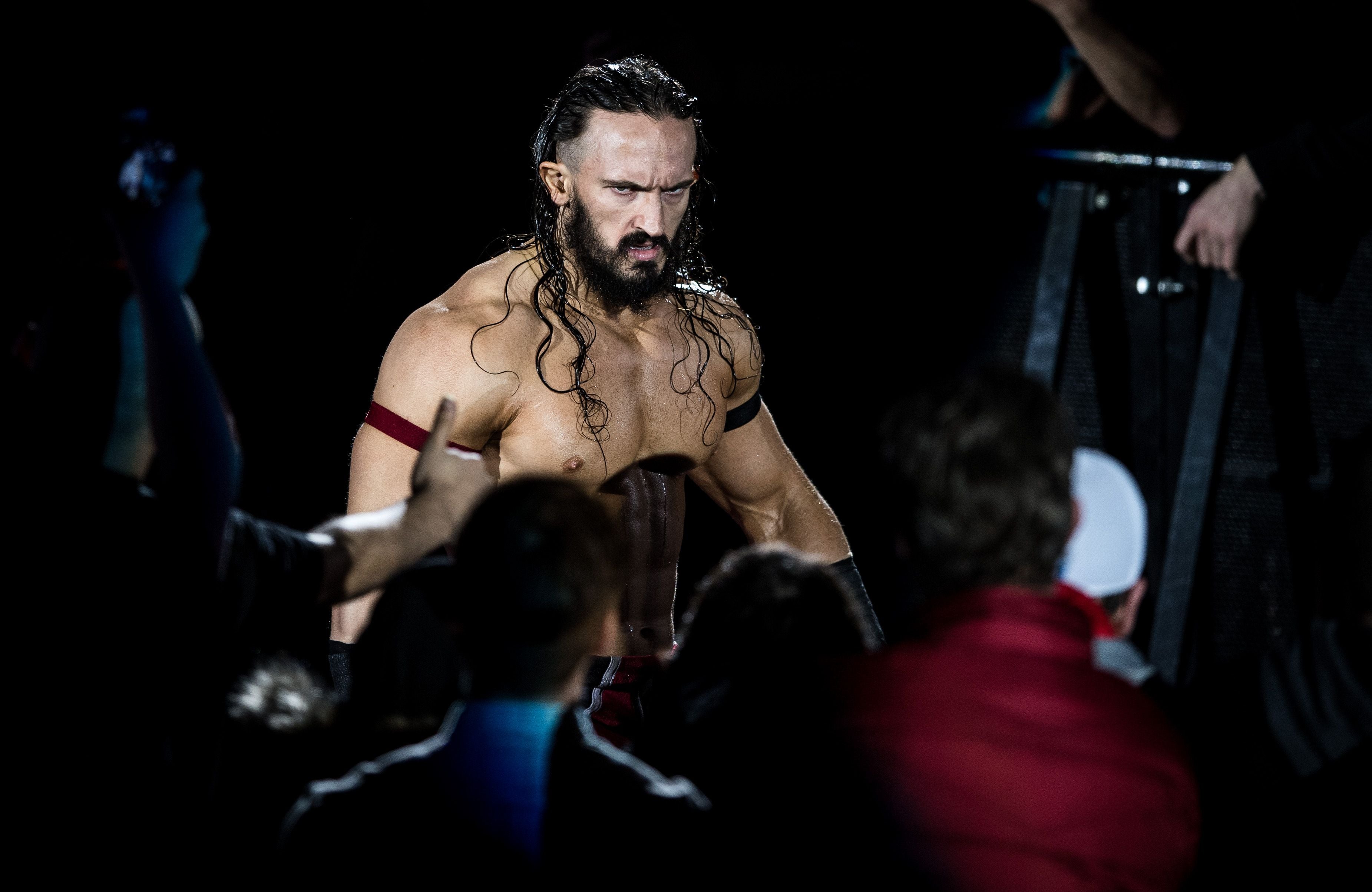 Ein muskulöser Wrestler mit langen Haaren läuft durch eine Menge bei einer WWE-Veranstaltung.