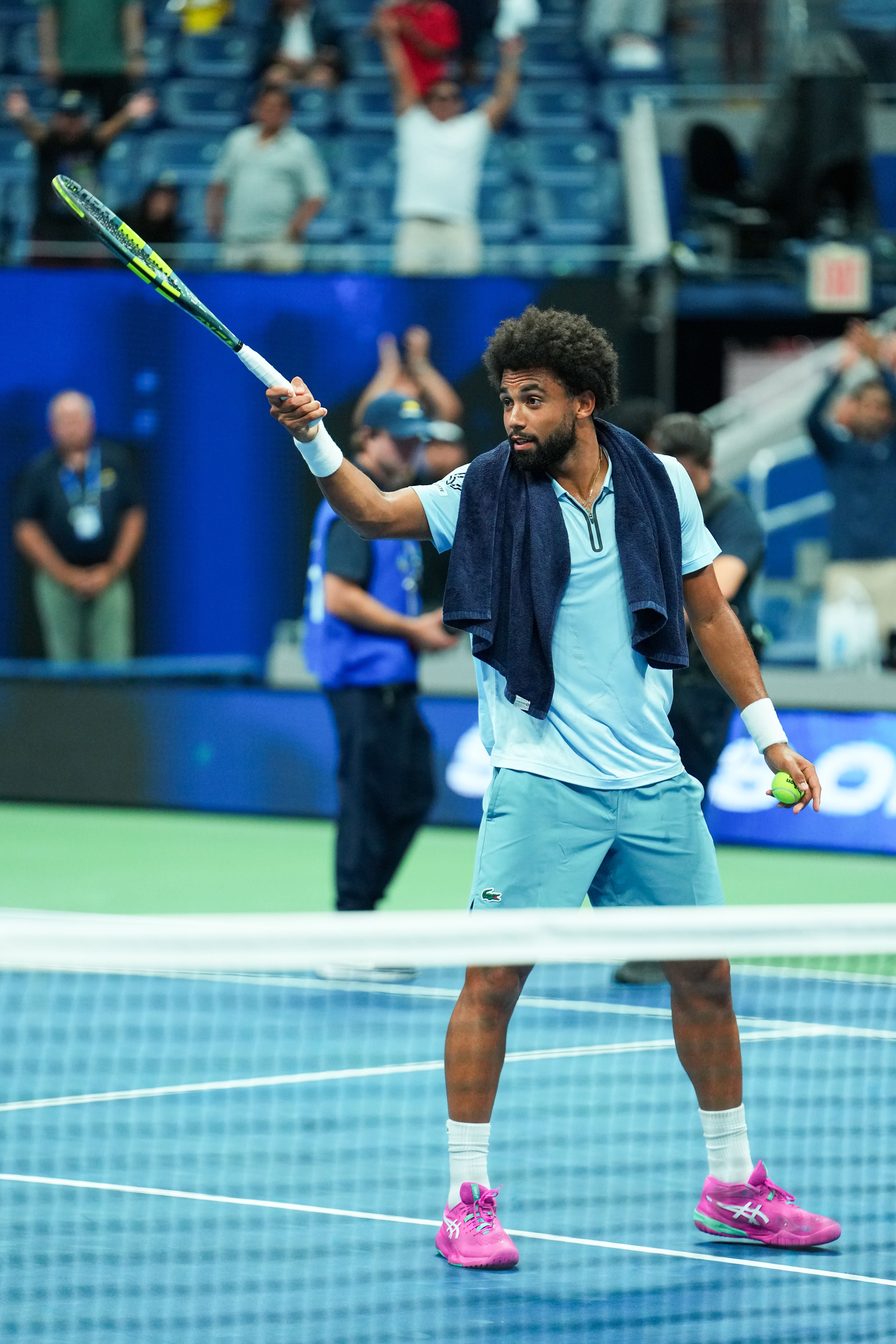 Ein Tennisspieler steht auf dem Platz, hält einen Schläger und hat ein Handtuch um den Nacken.