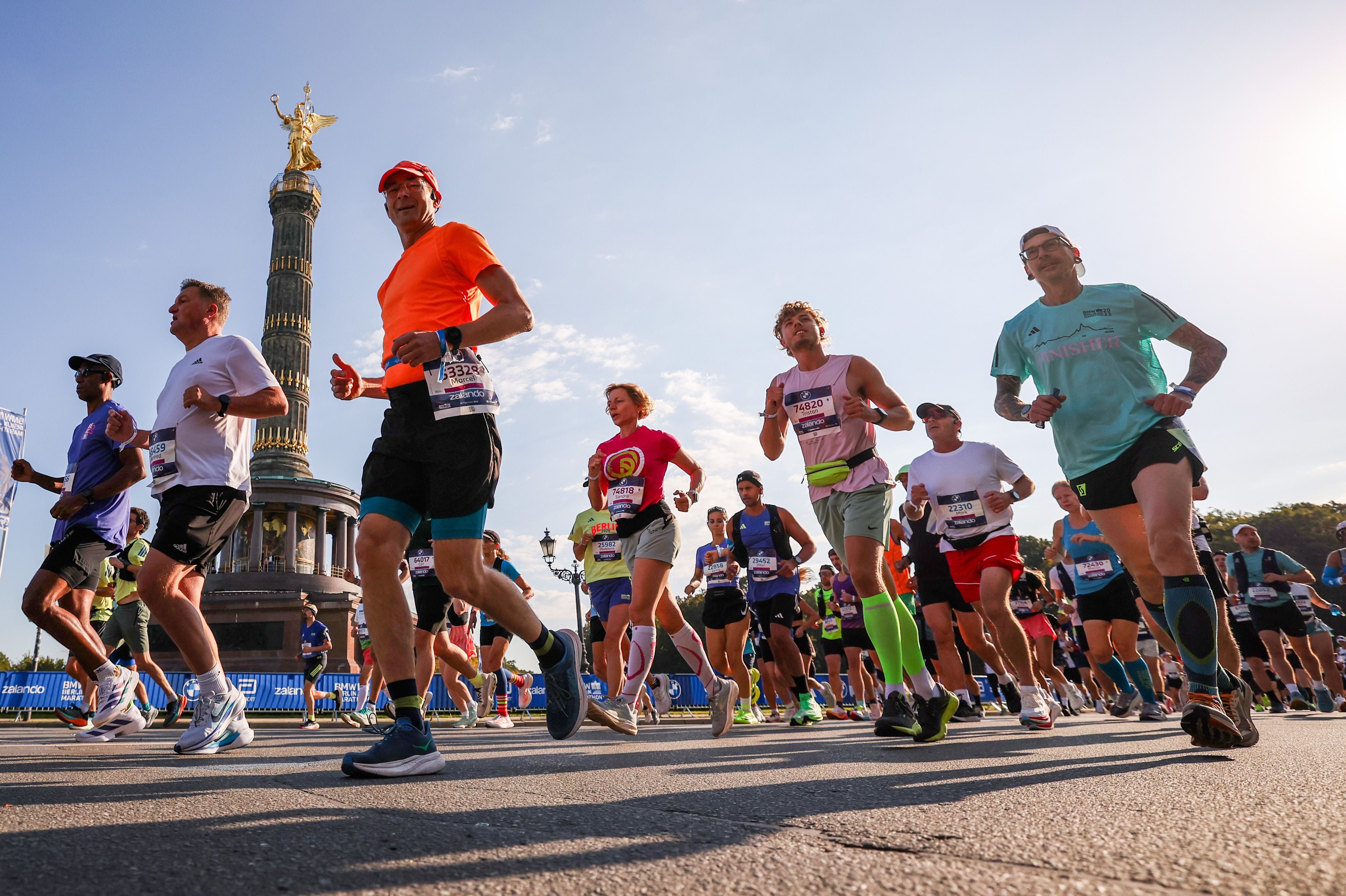 Läuferinnen und Läufer beim Berlin-Marathon 2026 vor der Siegessäule bei Sonnenschein.
