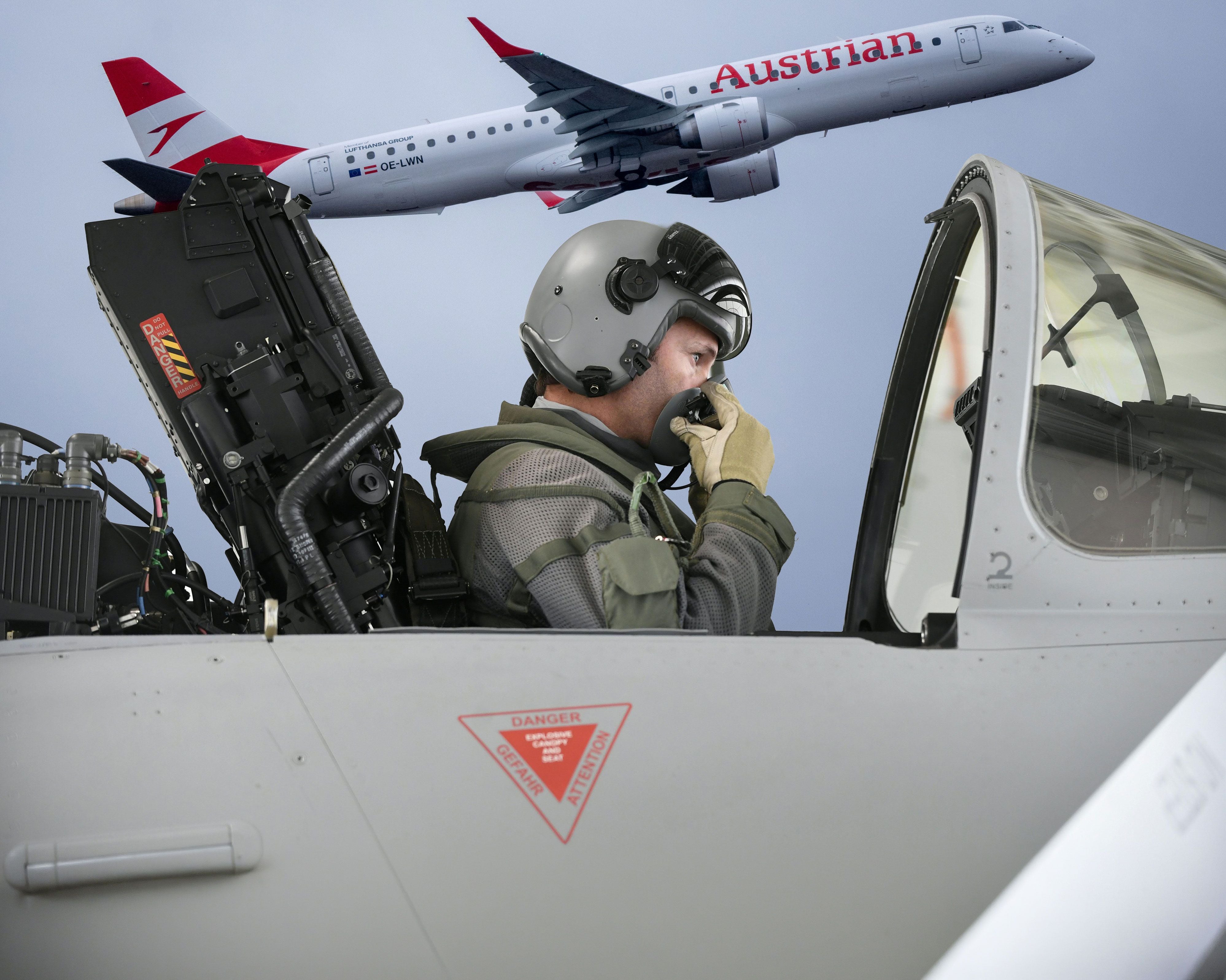 Pilot im Cockpit eines Kampfjets, darüber ein Austrian Airlines Flugzeug am Himmel.