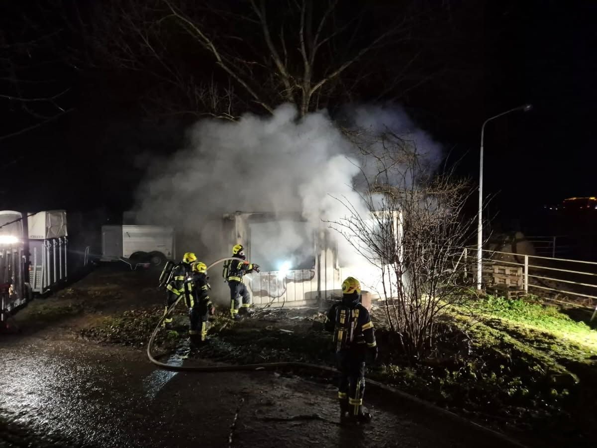 Feuerwehrleute löschen nachts einen brennenden, stark qualmenden Stall.
