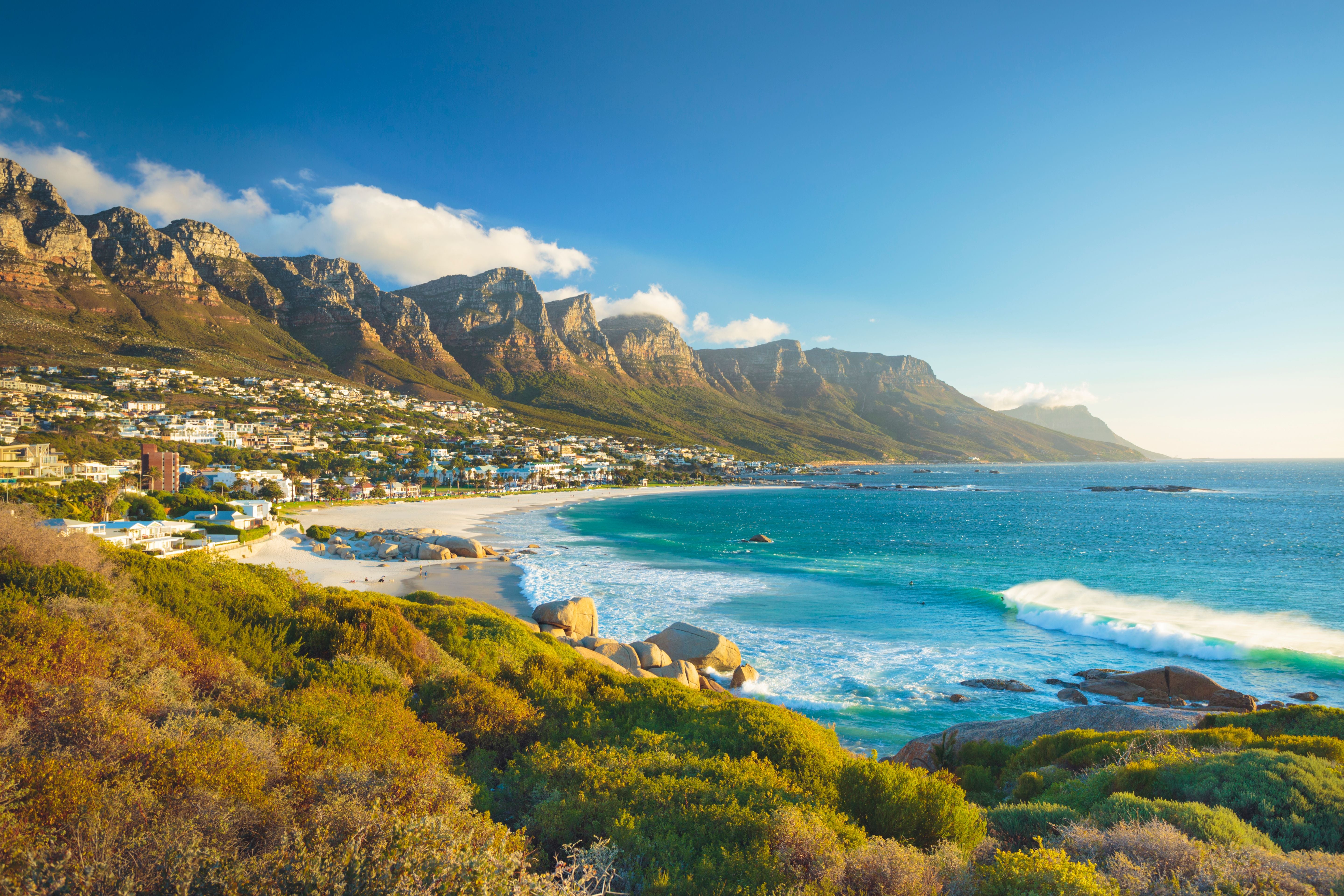Strand mit Wellen und den Twelve Apostles Bergen bei Camps Bay nahe Kapstadt, Südafrika.