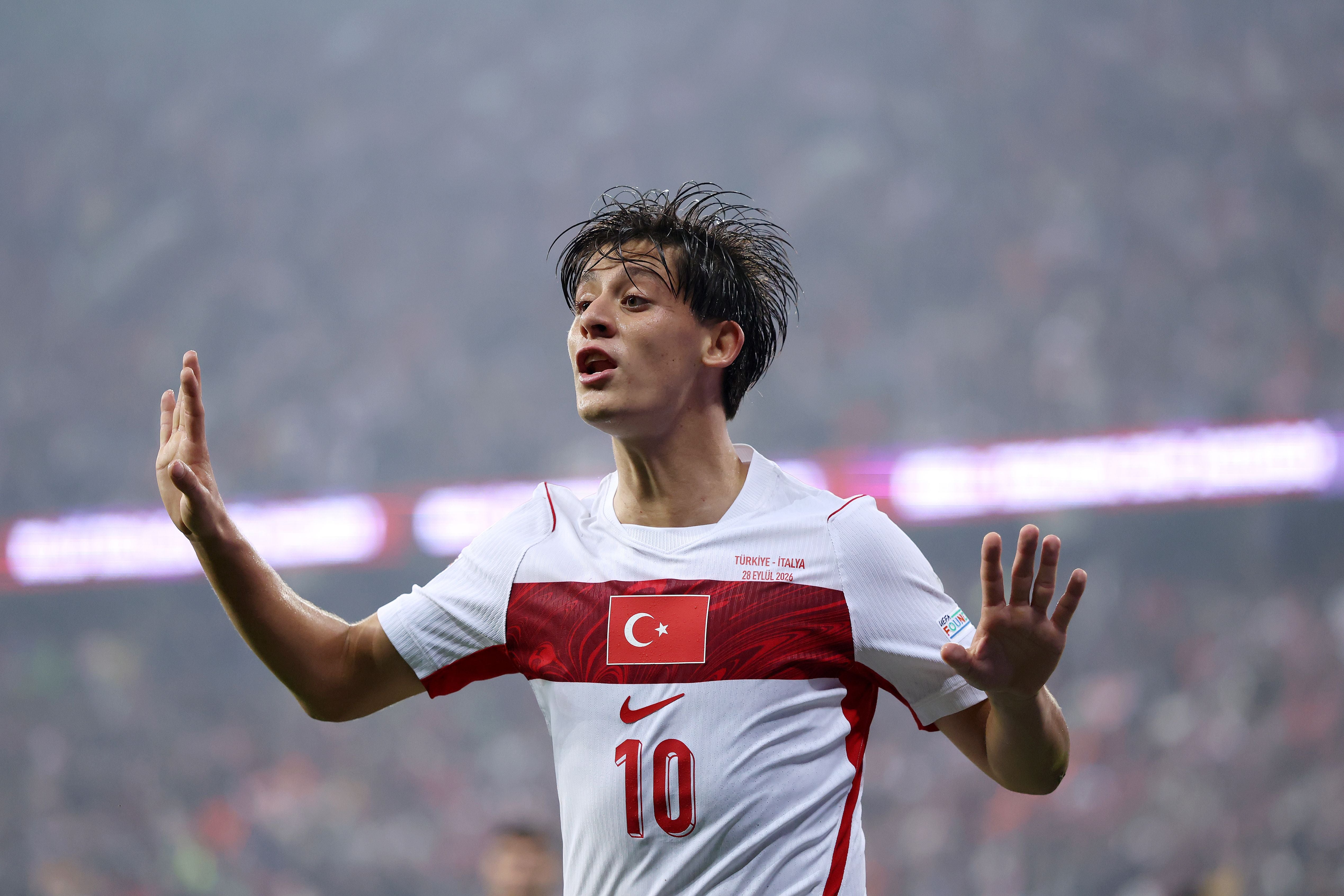 Ein türkischer Fußballspieler im weißen Trikot gestikuliert während eines Spiels im Stadion.