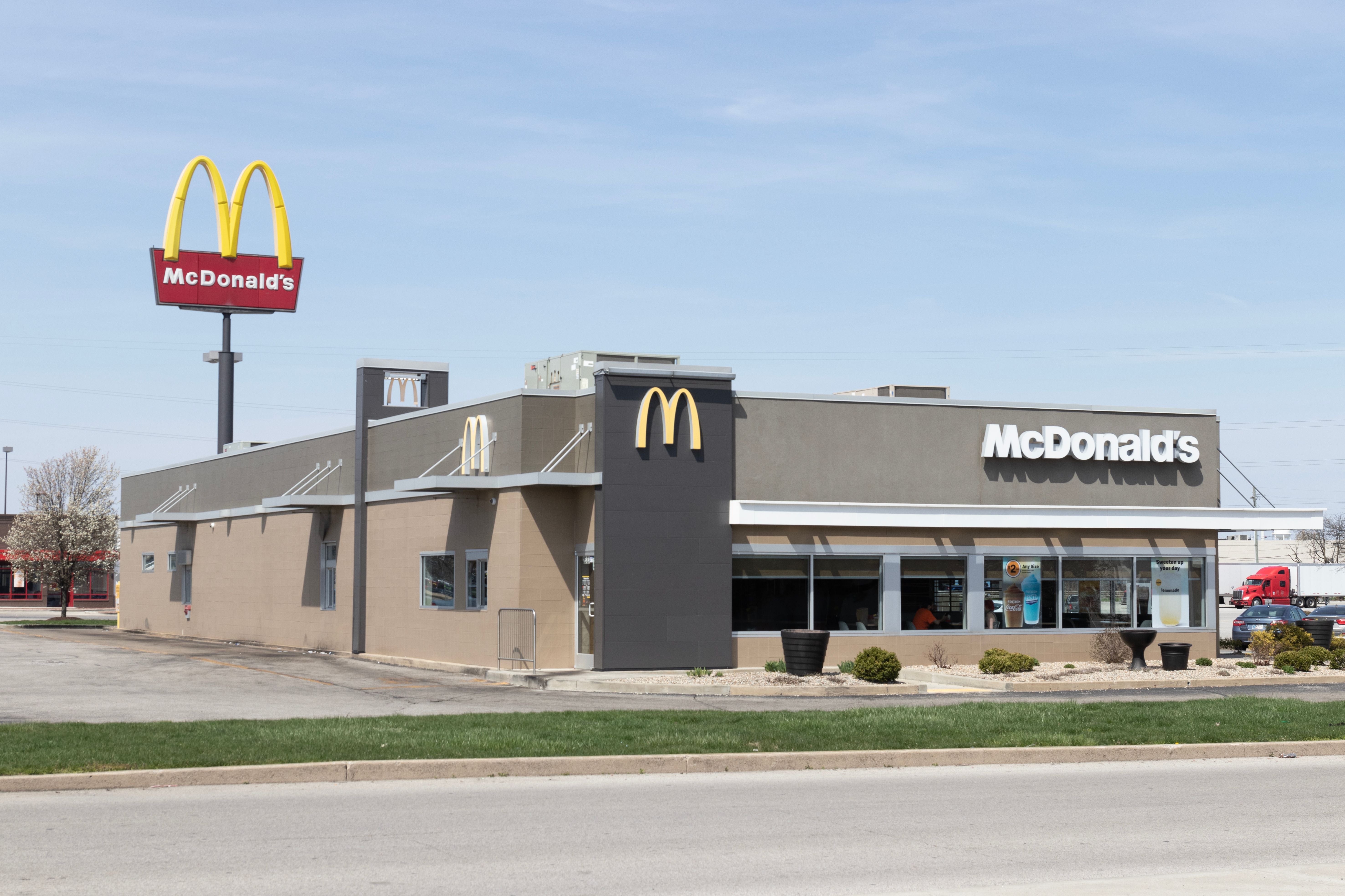 McDonald's Restaurant mit großem gelben M-Logo und Parkplatz im Vordergrund.