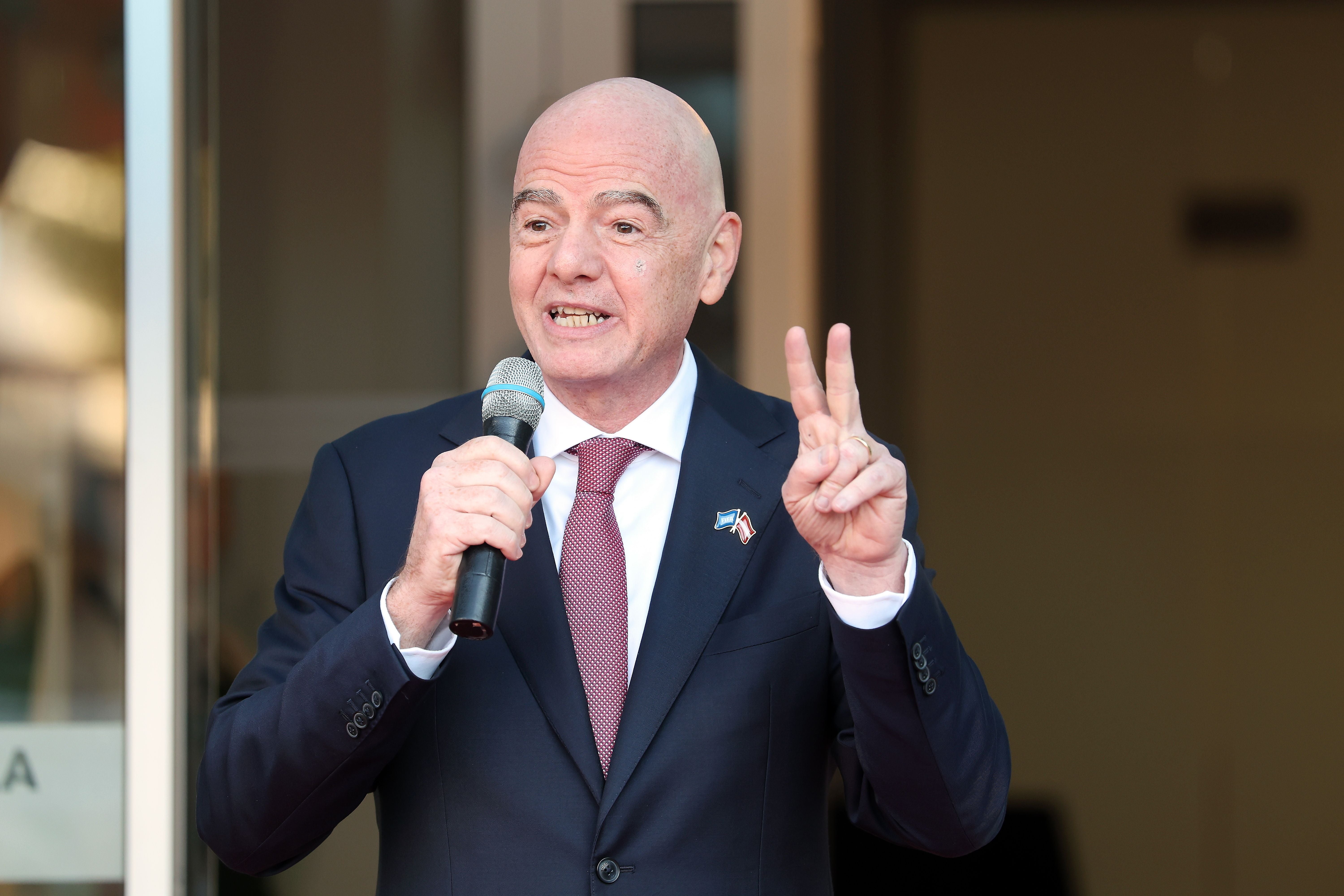 Ein Mann im Anzug spricht mit Mikrofon und zeigt das Victory-Zeichen mit der Hand.