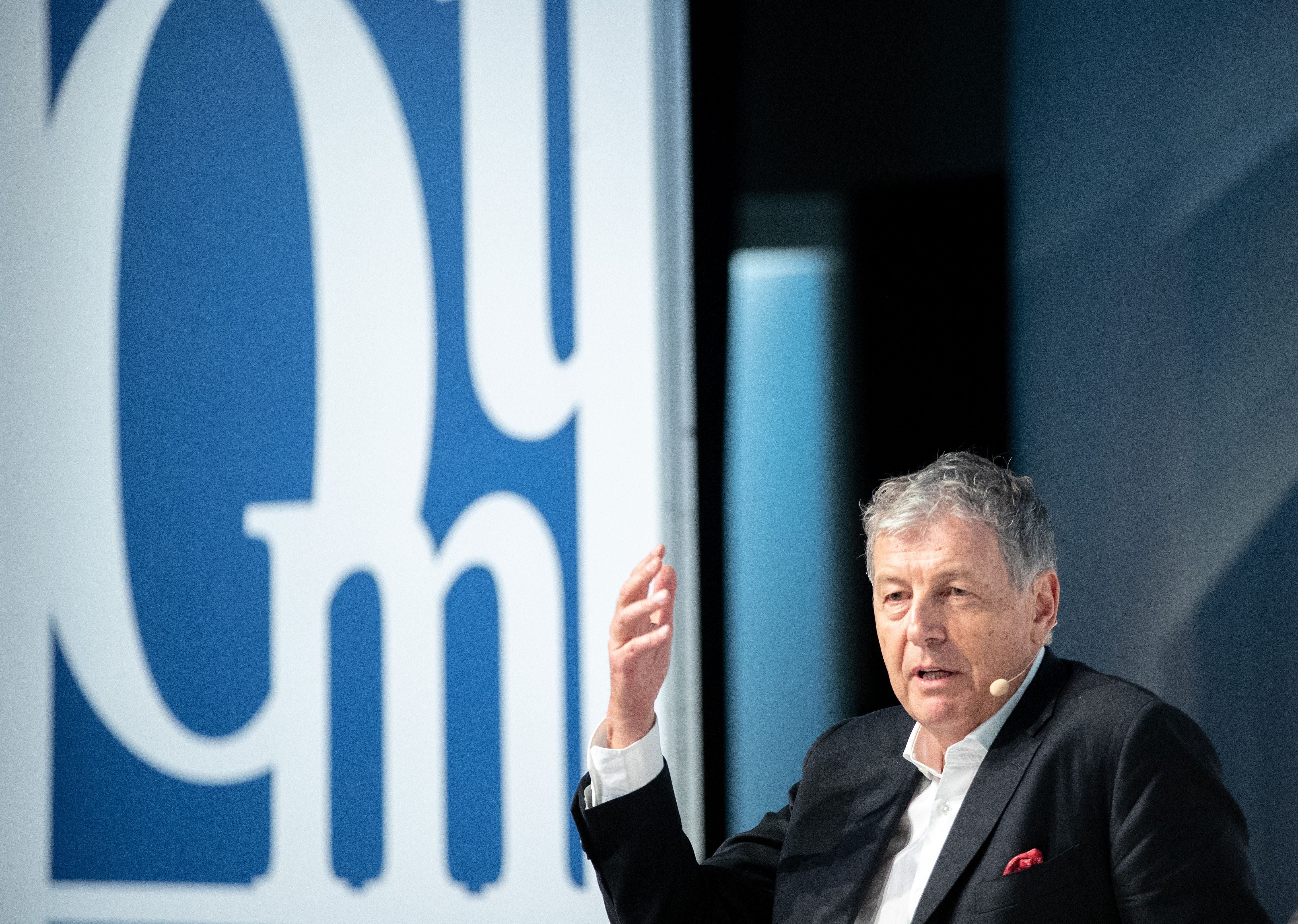 Gerhard Zeiler spricht bei einer Veranstaltung, trägt Mikrofon und hebt die Hand.
