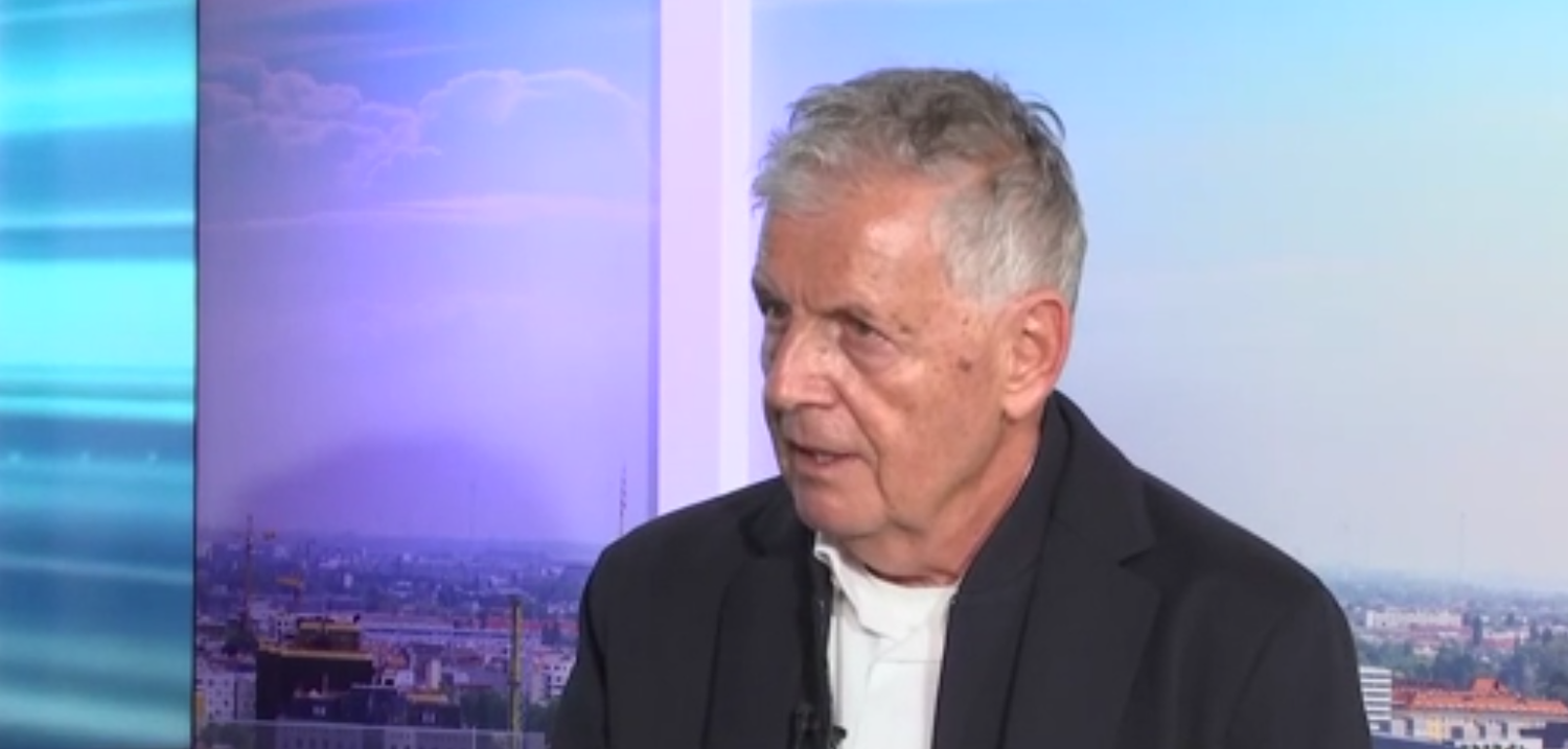 Ein älterer Mann mit grauen Haaren im Anzug spricht in einem Fernsehstudio.