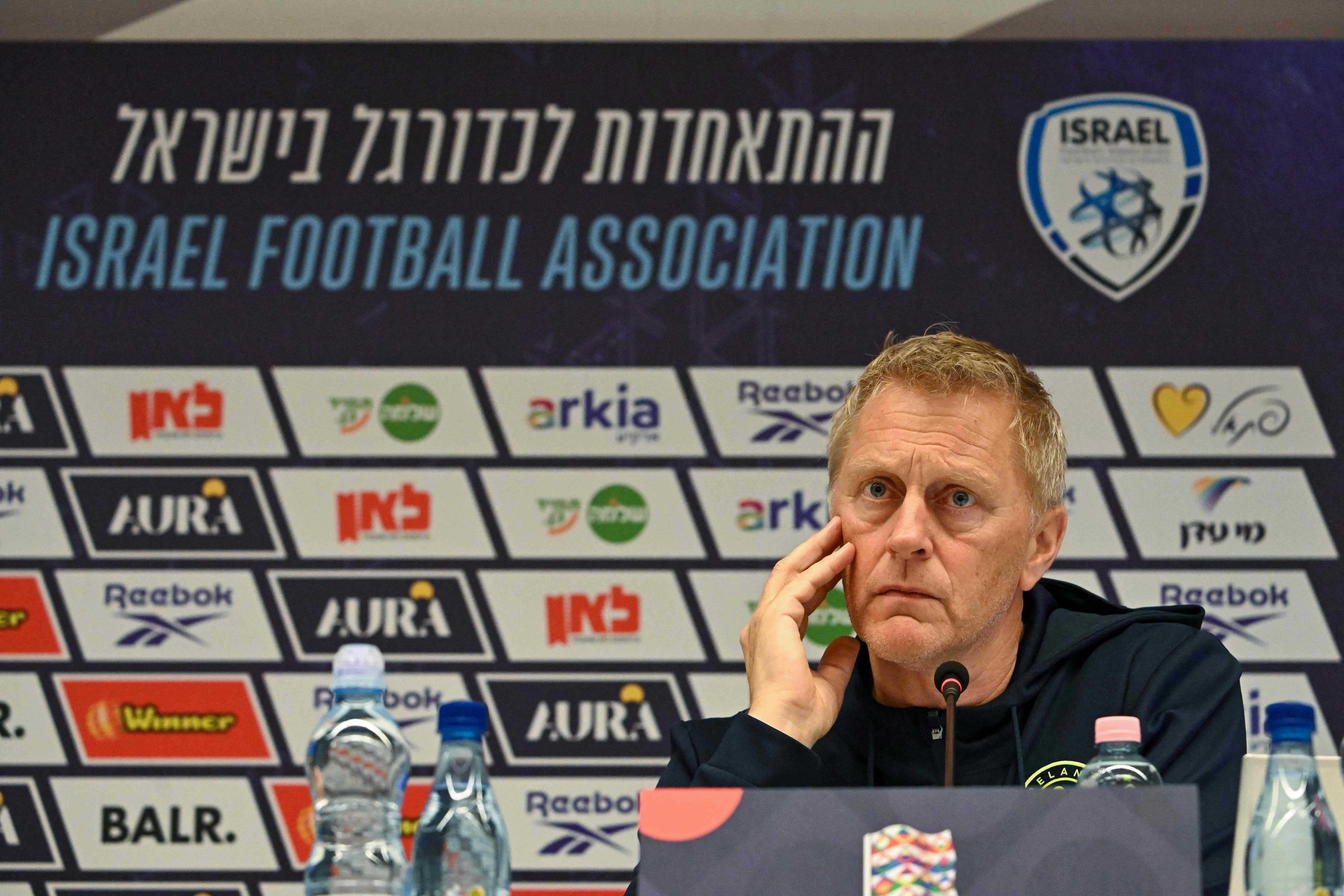 Ein Mann sitzt nachdenklich bei einer Pressekonferenz vor einem Schild der Israel Football Association.