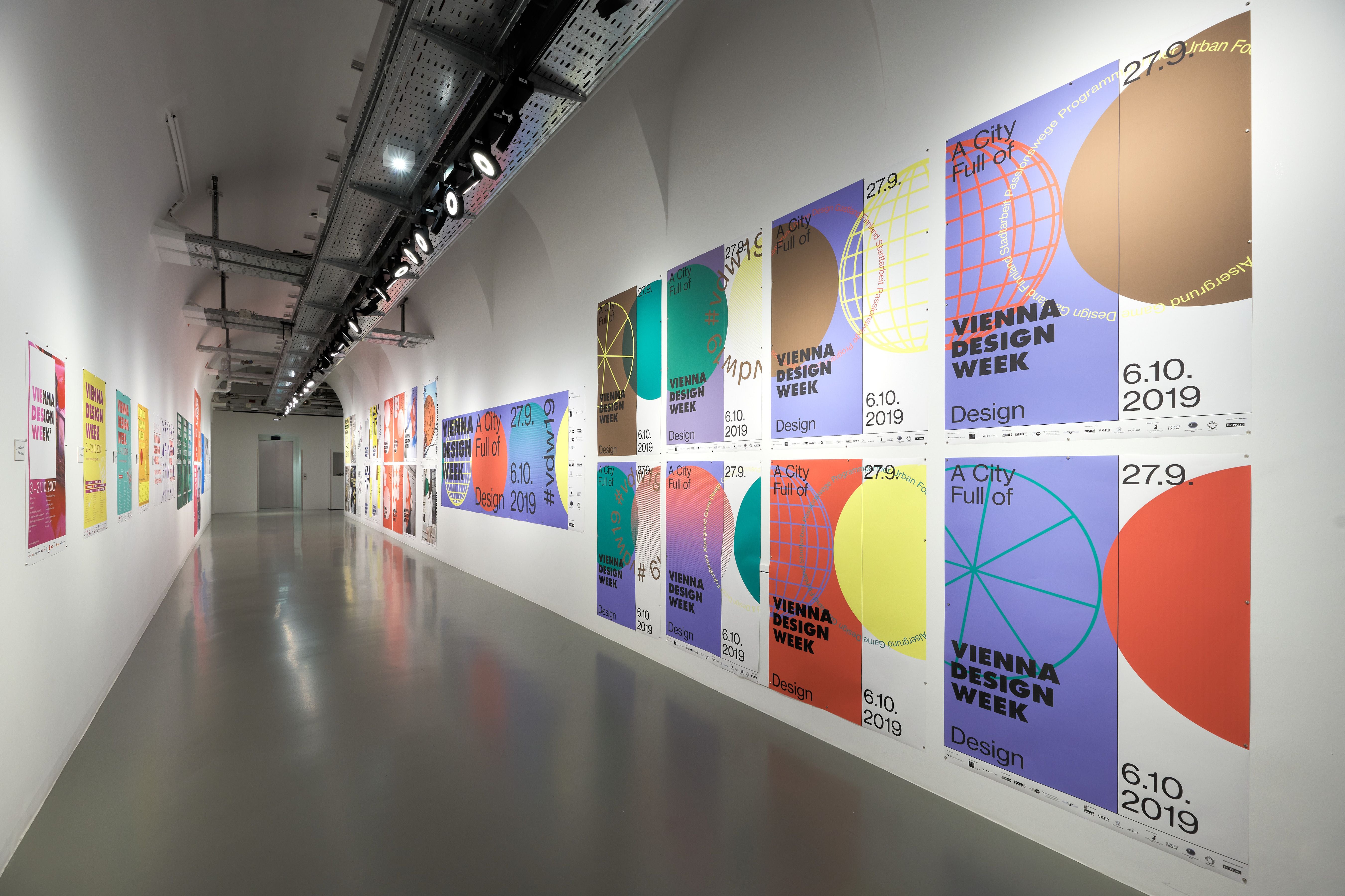 Ausstellungsraum mit bunten Postern der Vienna Design Week an weißen Wänden.