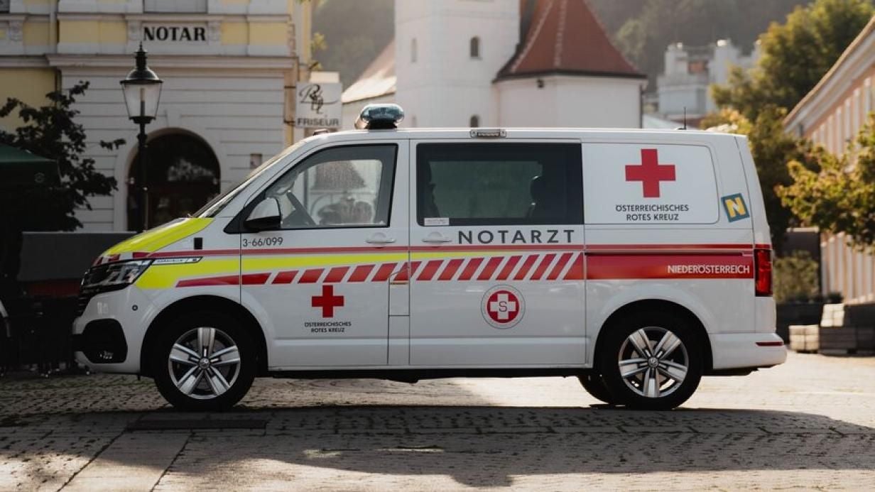 Ein Notarztwagen des Österreichischen Roten Kreuzes steht auf einem Stadtplatz.