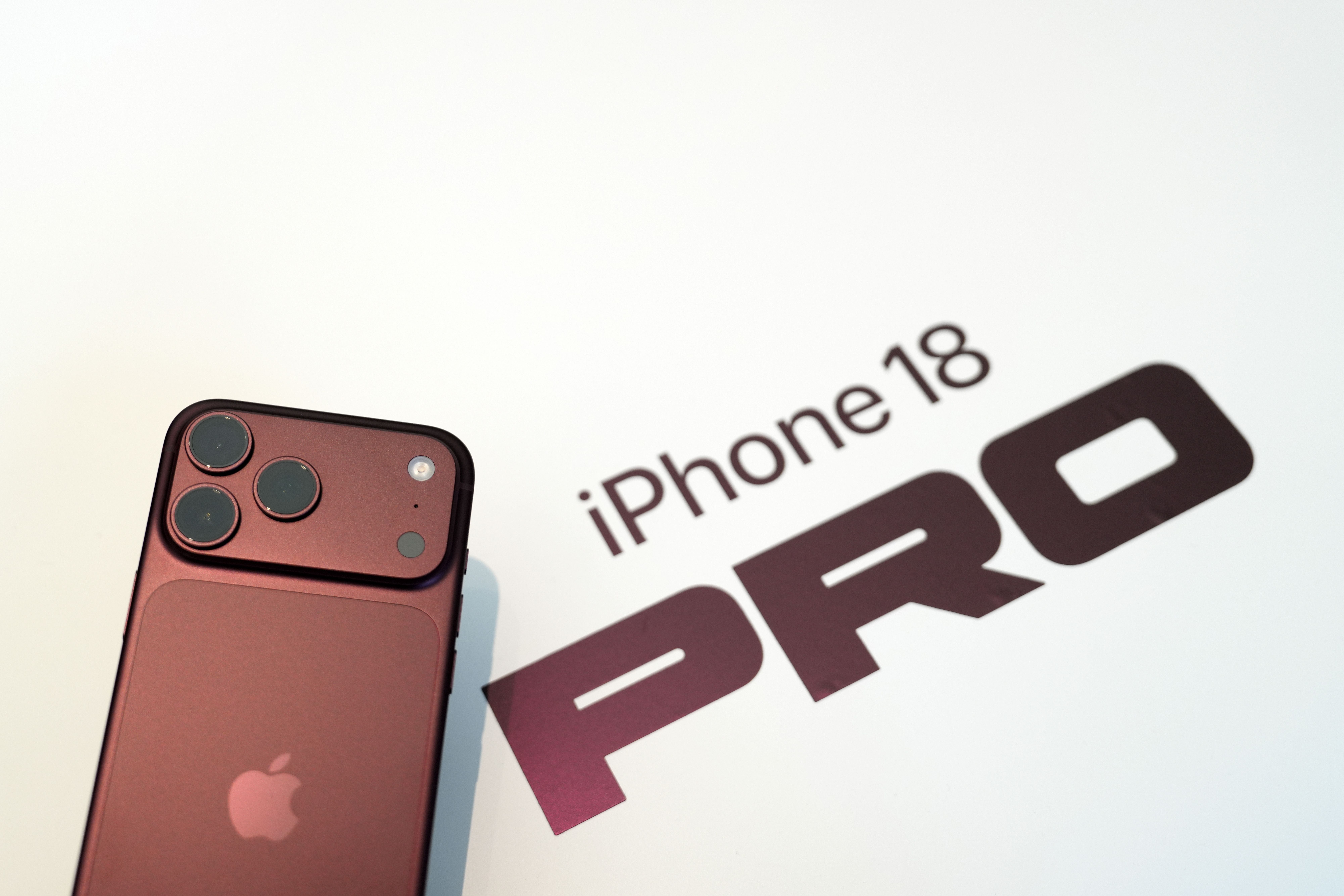 Ein rotes iPhone 18 Pro liegt auf einer weißen Fläche mit dem Schriftzug „iPhone 18 PRO“.