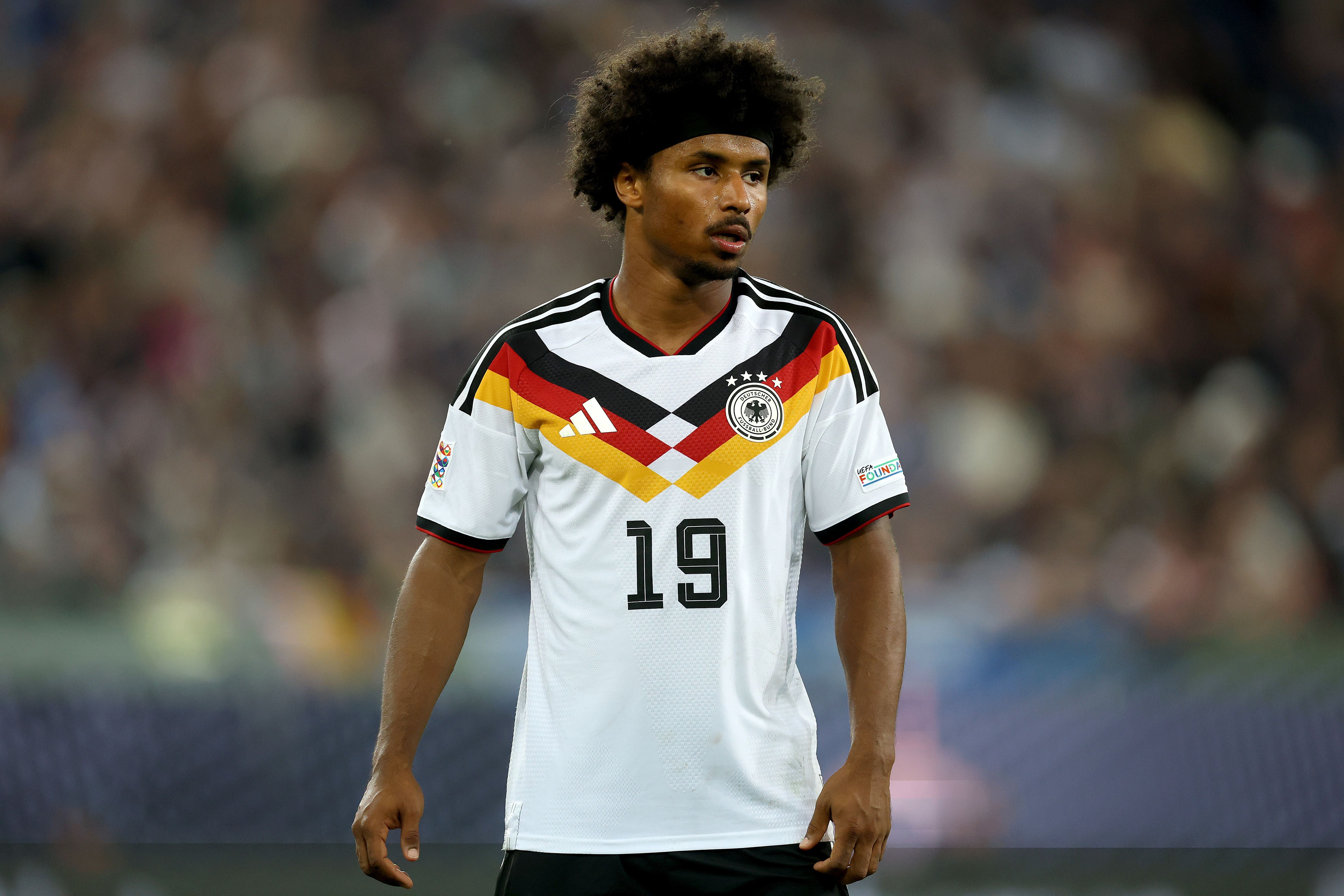 Ein Fußballspieler im weißen Deutschland-Trikot mit der Nummer 19 steht auf dem Spielfeld.