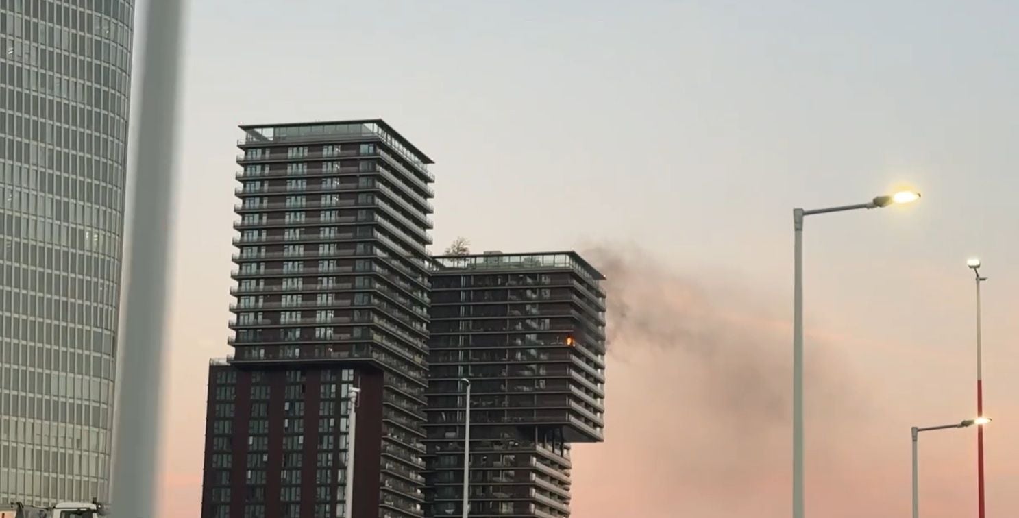 Rauch und Flammen kommen aus einem Fenster der Triiiple Towers bei Sonnenuntergang.
