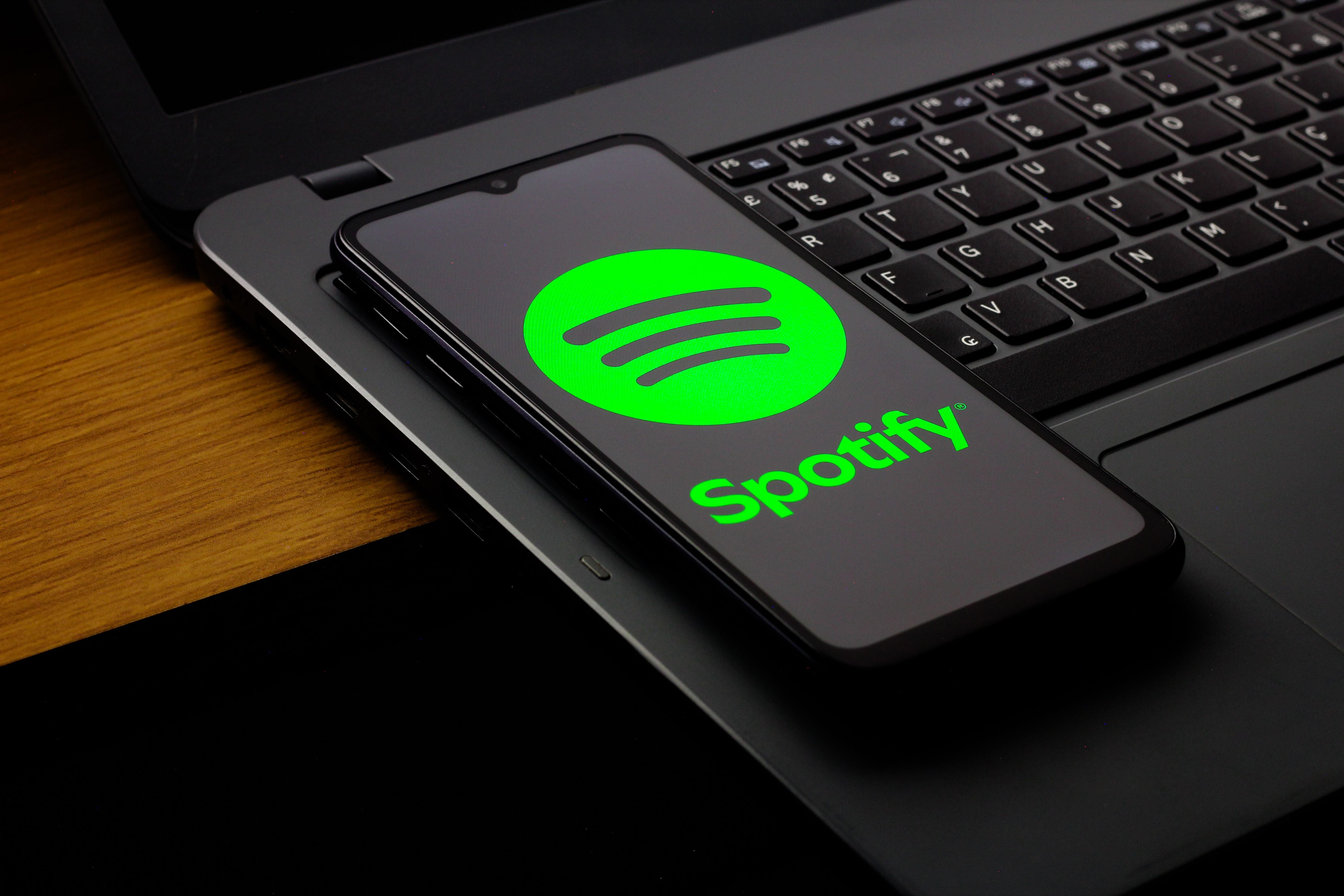 Ein Smartphone mit Spotify-Logo liegt auf einer Laptop-Tastatur.