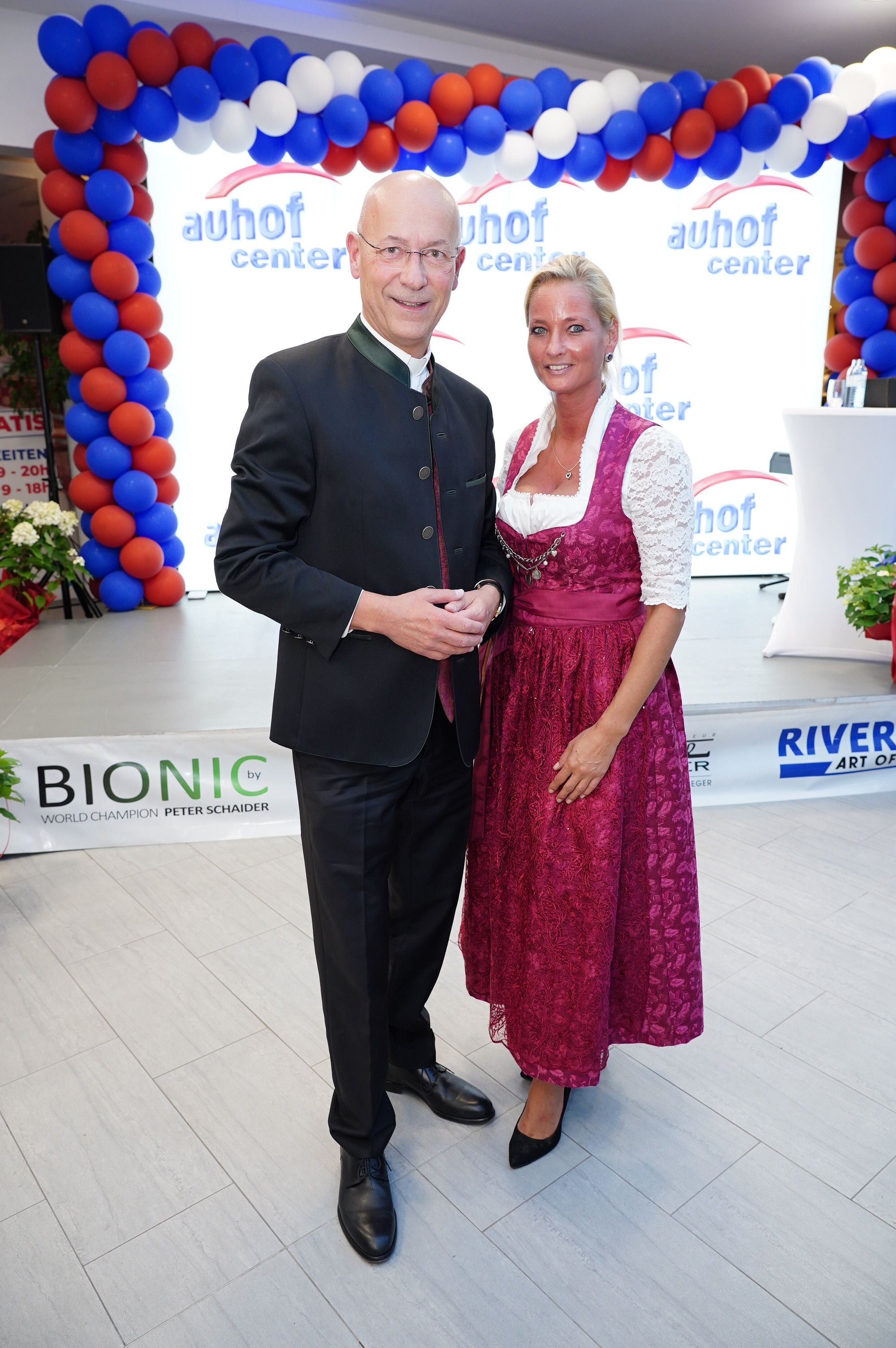 Ein Mann in Tracht und eine Frau im Dirndl posieren vor einer Ballon-Dekoration im Auhofcenter.