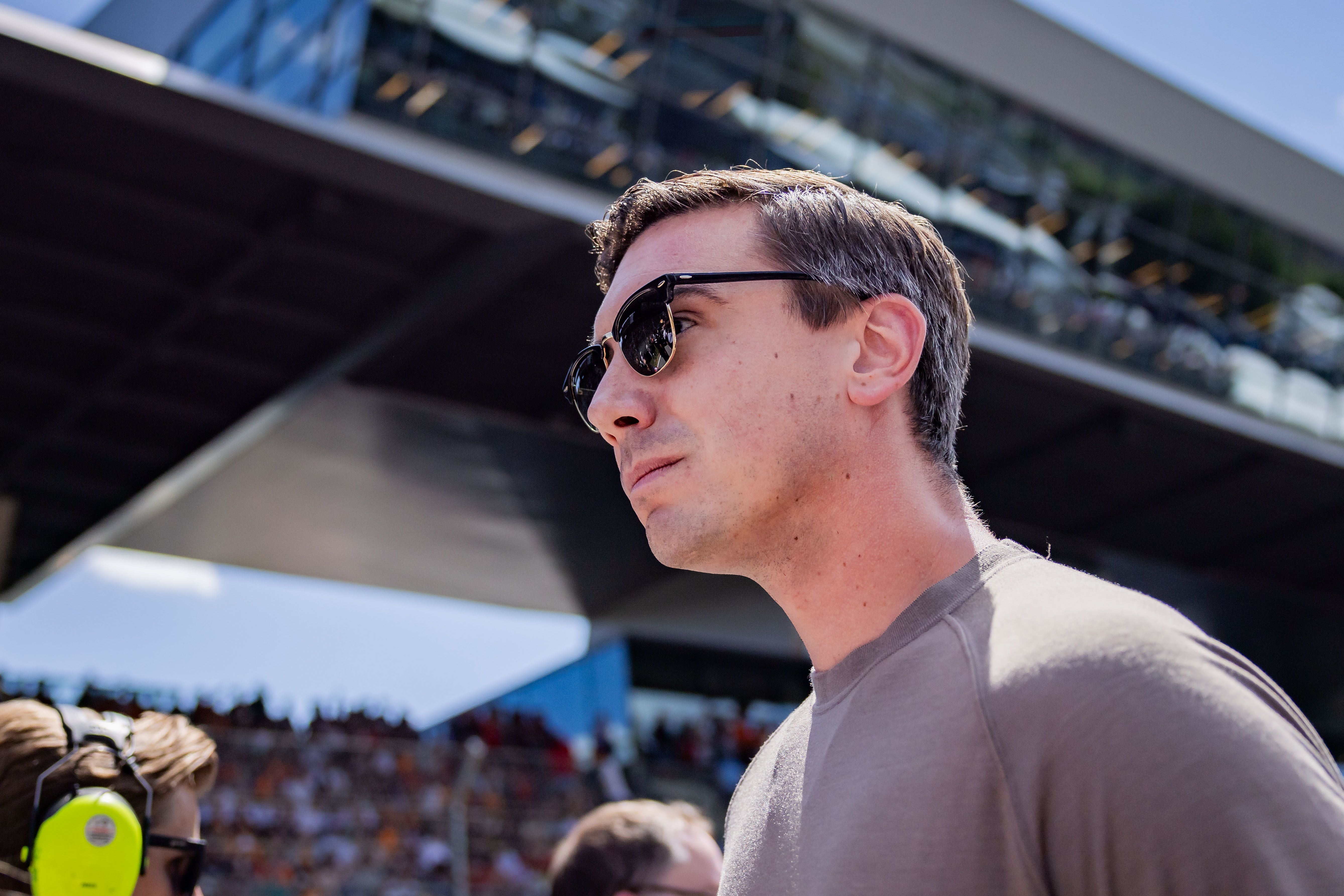 Ein Mann mit Sonnenbrille steht vor einer überdachten Tribüne am Red Bull Ring.