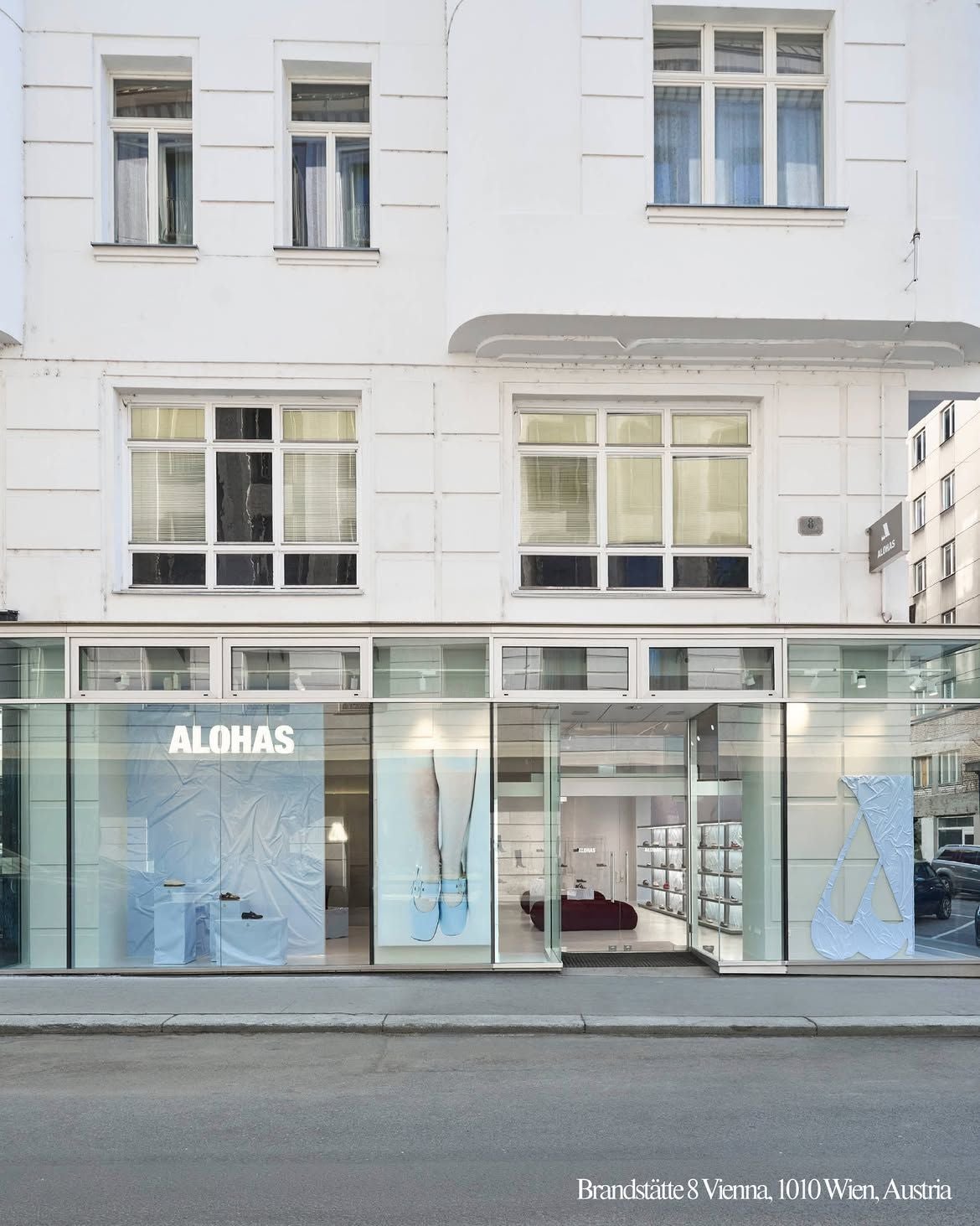 Straßenansicht eines hellen ALOHAS-Schuhgeschäfts mit großer Glasfassade in Wien.