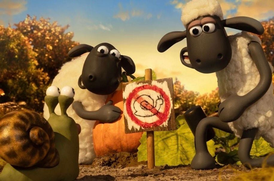 Shaun das Schaf und ein weiteres Schaf betrachten ein Schild mit Schnecken-Verbotssymbol.
