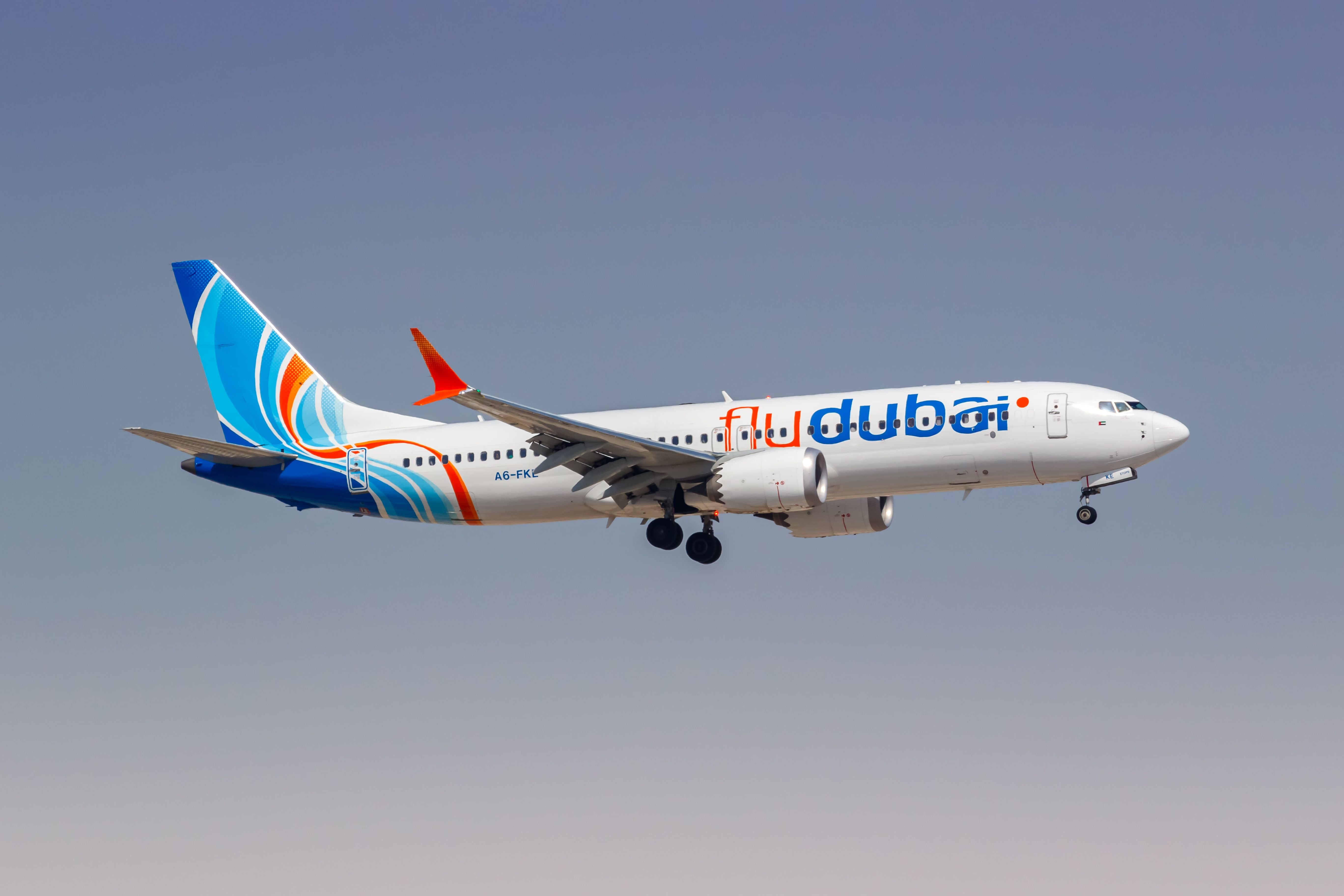 FlyDubai Boeing 737 MAX 8 im Landeanflug am Flughafen Dubai vor blauem Himmel.