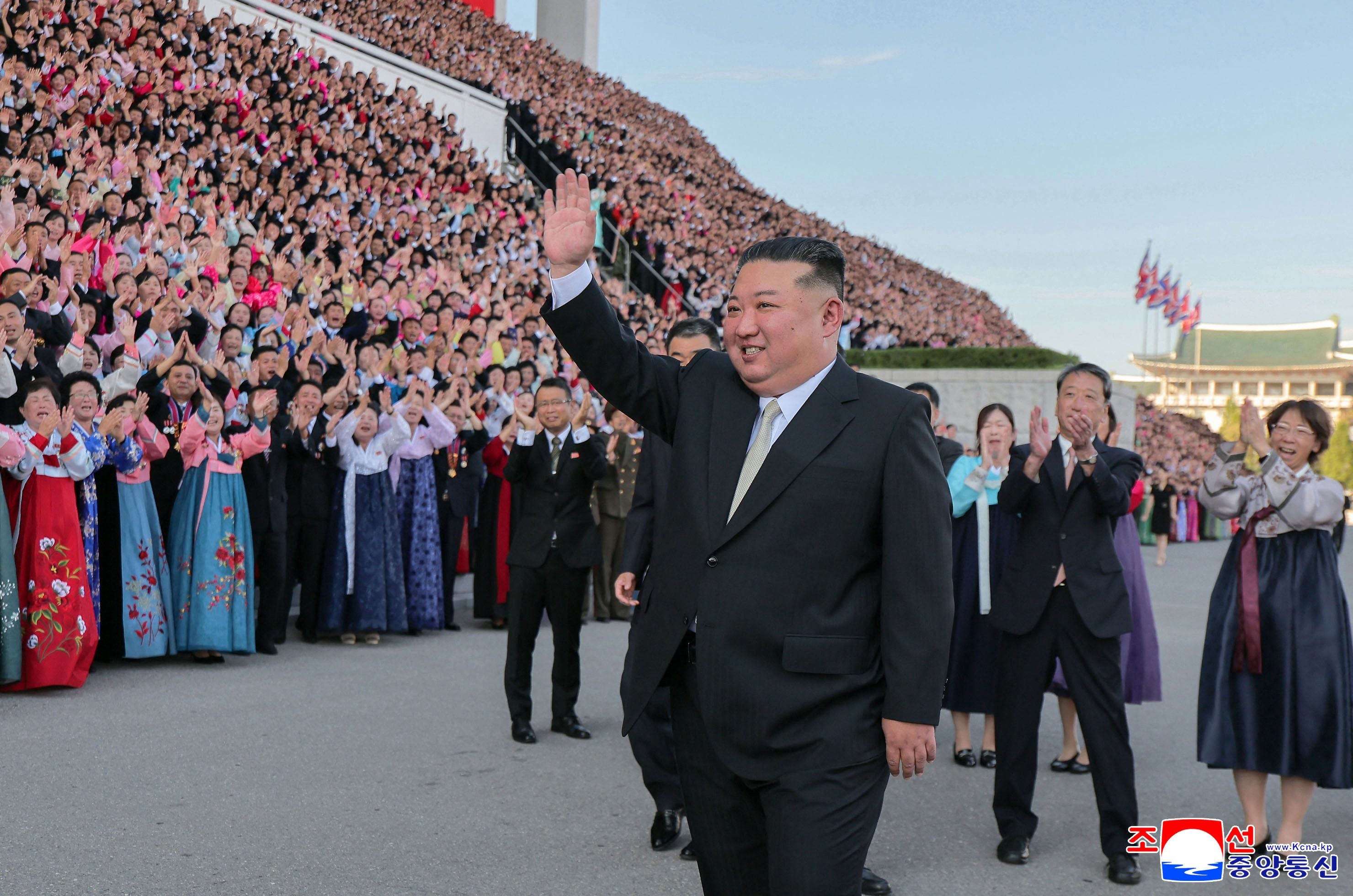 Kim Jong Un winkt einer jubelnden Menschenmenge bei einer Veranstaltung im Freien zu.