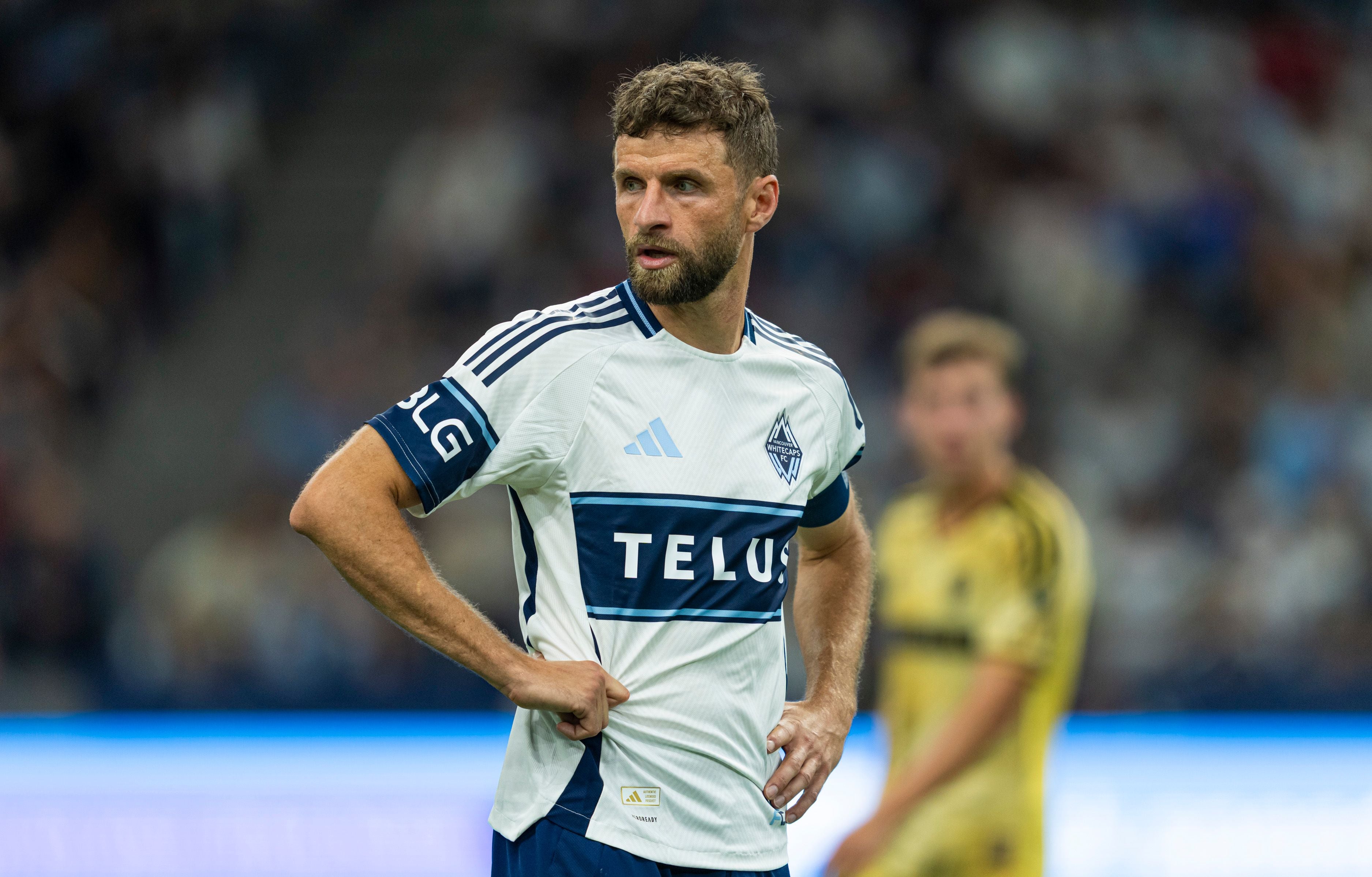 Ein Fußballspieler der Vancouver Whitecaps steht mit Händen in den Hüften auf dem Spielfeld.