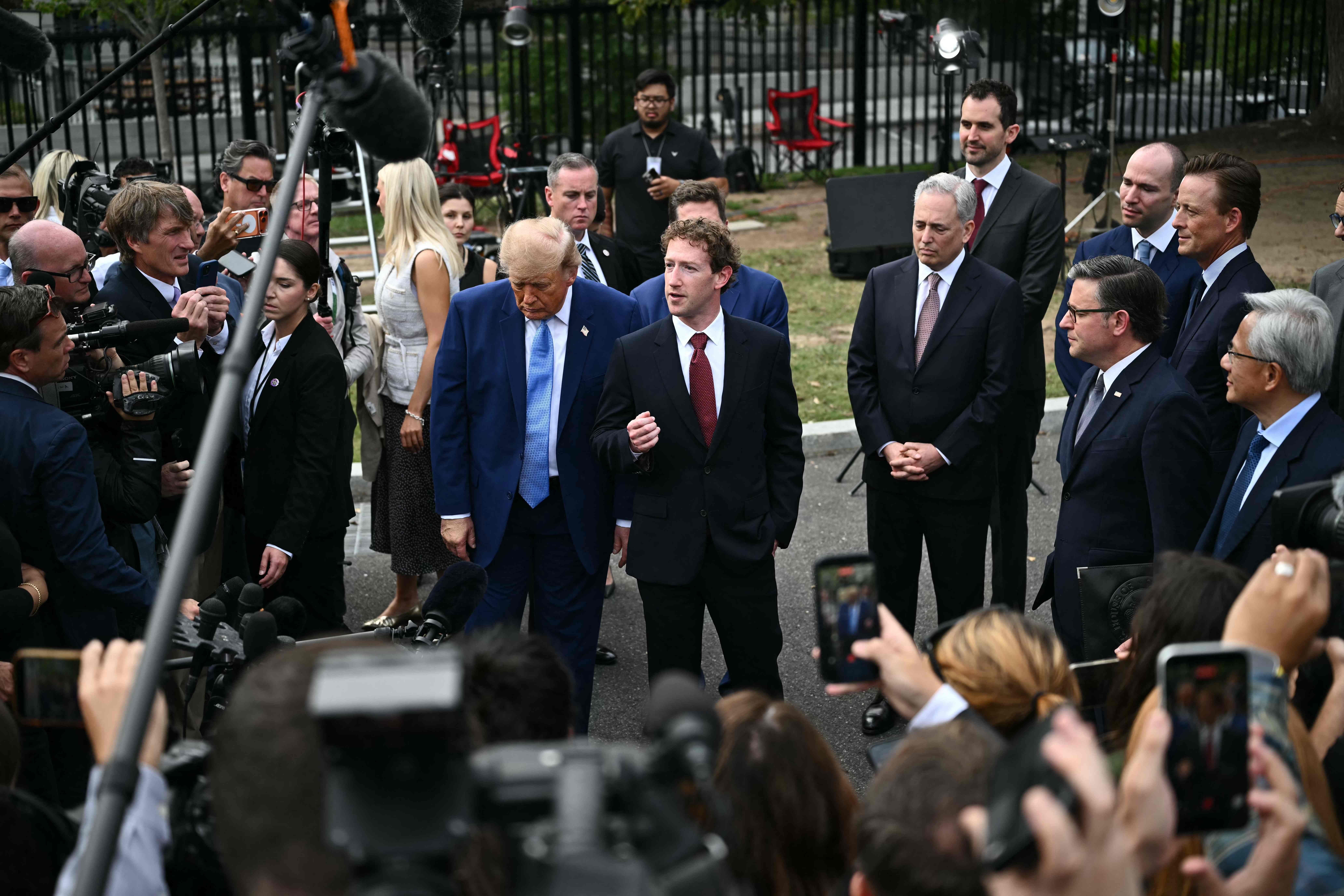 Mark Zuckerberg spricht zur Presse, während Donald Trump und andere Anzugträger zuhören.