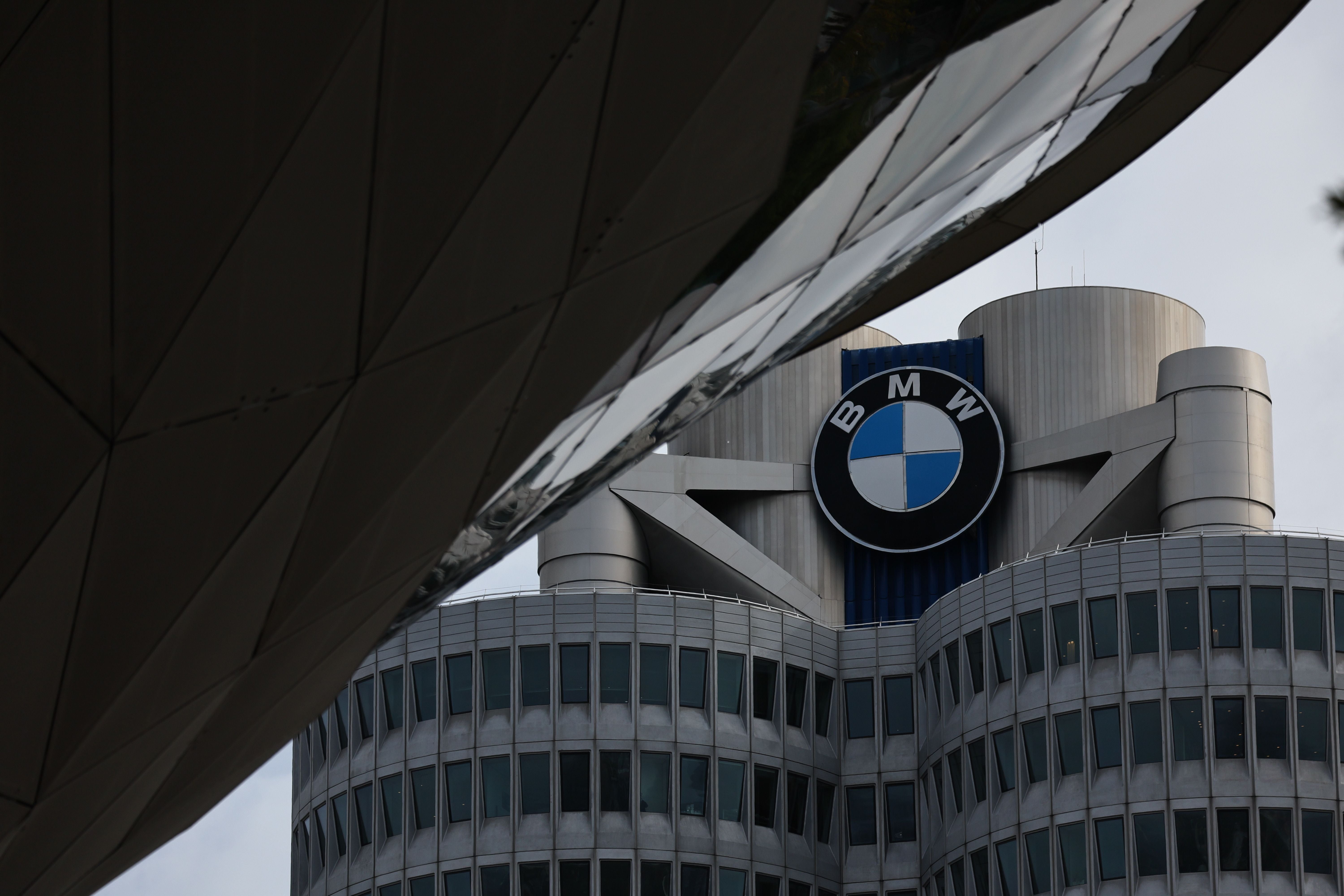 Das BMW-Hochhaus mit großem BMW-Logo in München, teilweise von Gebäudeteilen verdeckt.