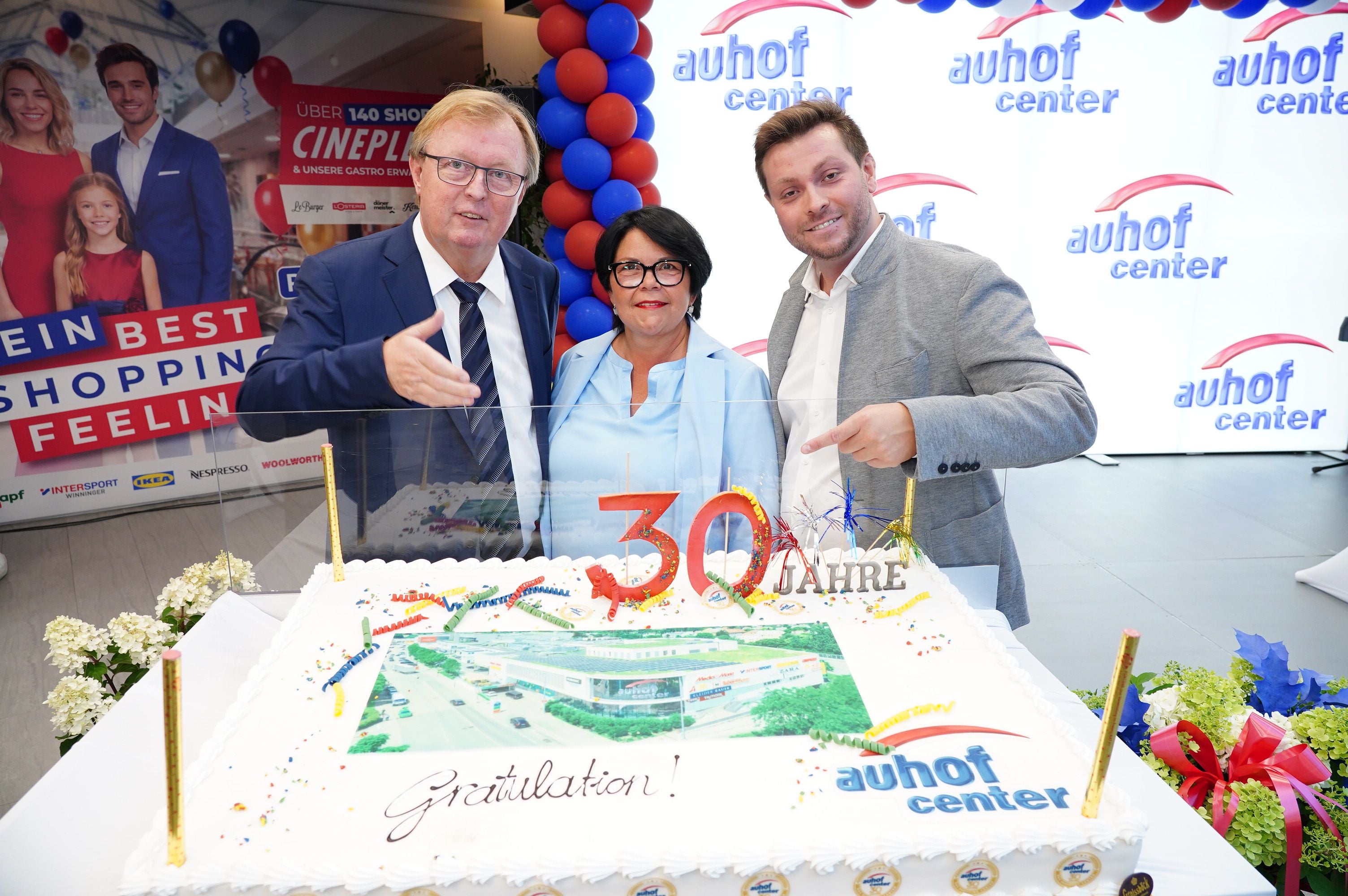 Drei Personen feiern mit einer großen Torte das 30-jährige Jubiläum des Auhof Centers.
