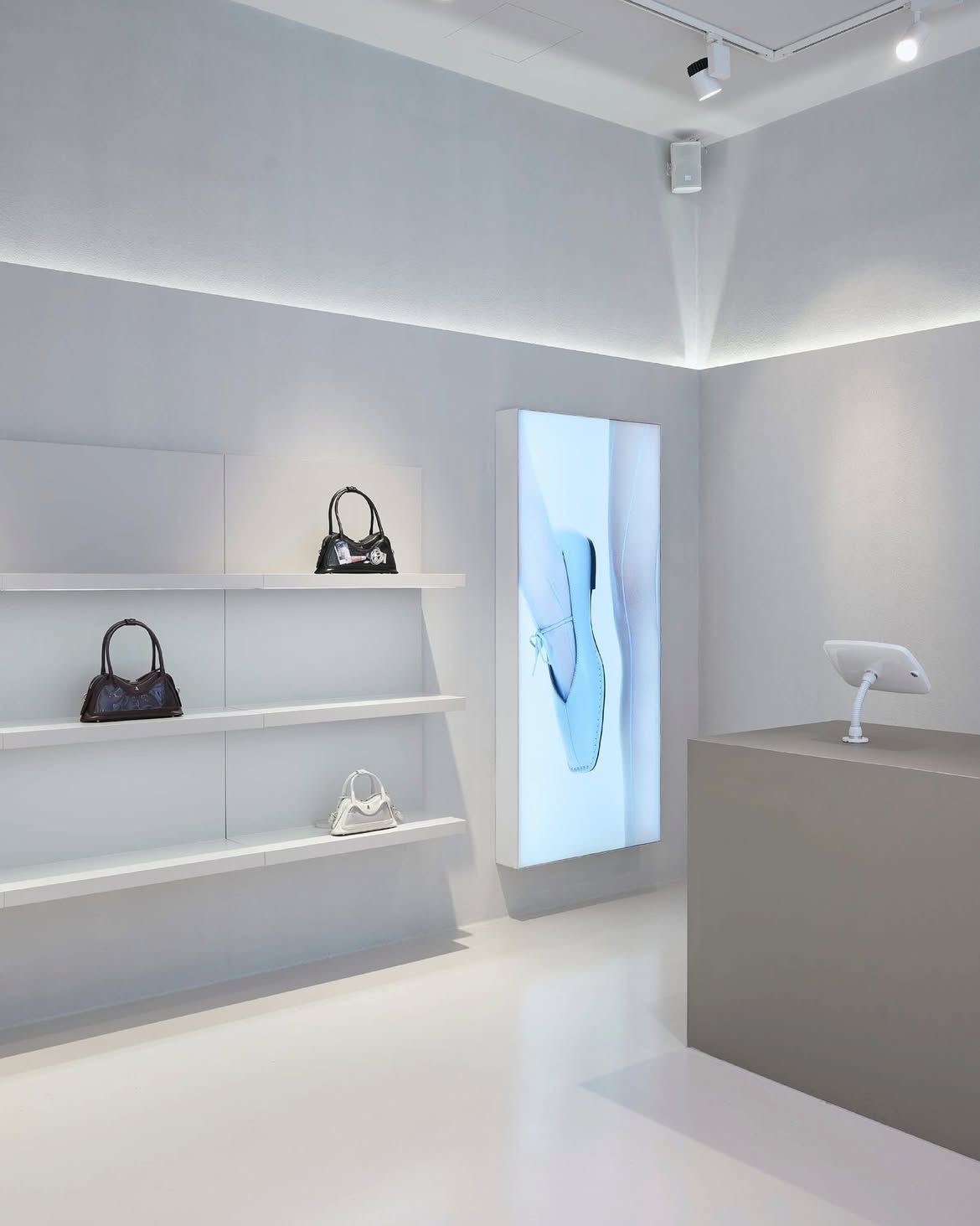 Moderner, minimalistischer Shop mit weißen Regalen, Handtaschen und digitaler Werbetafel.