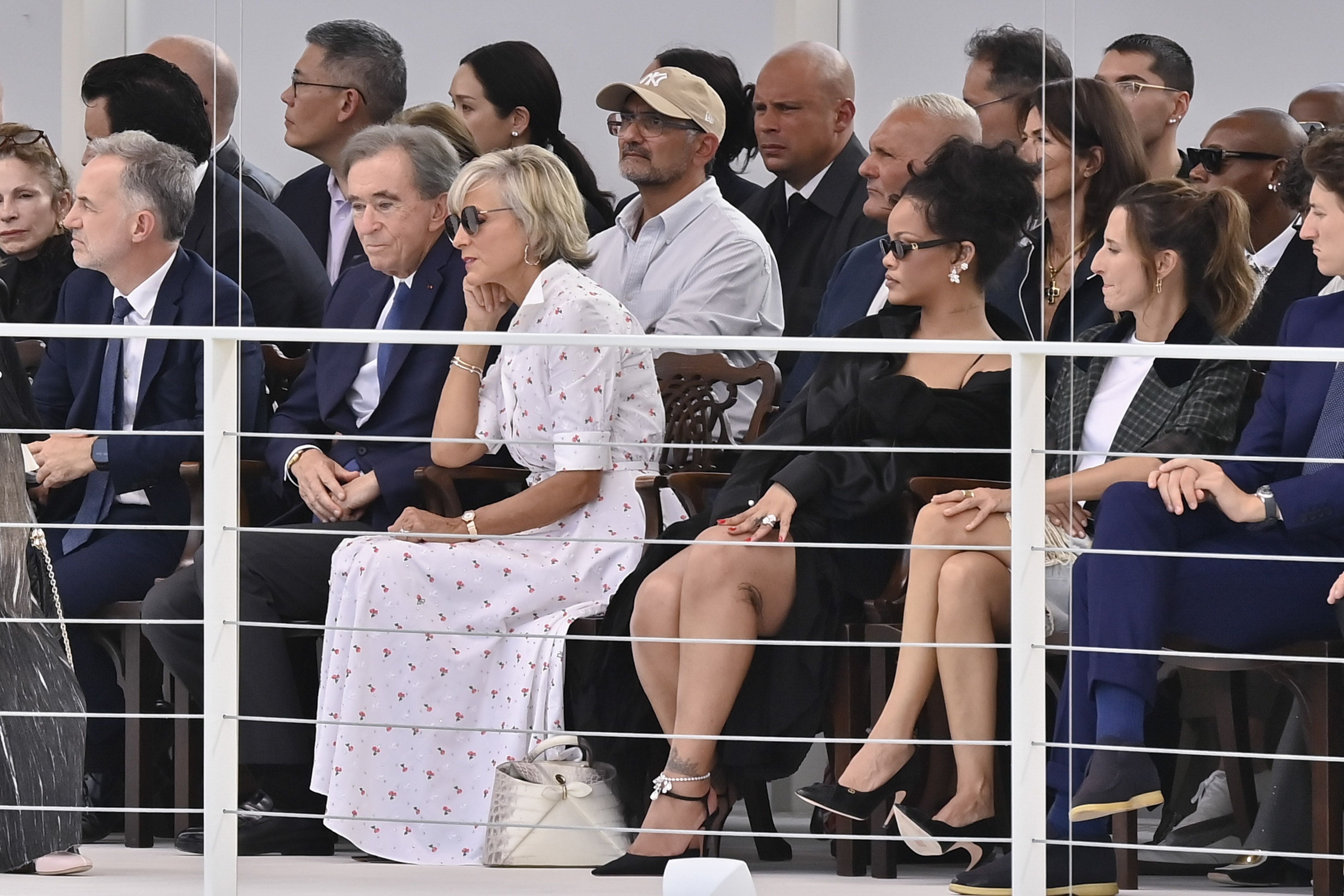 Mehrere elegant gekleidete Gäste sitzen in der ersten Reihe einer Modenschau.