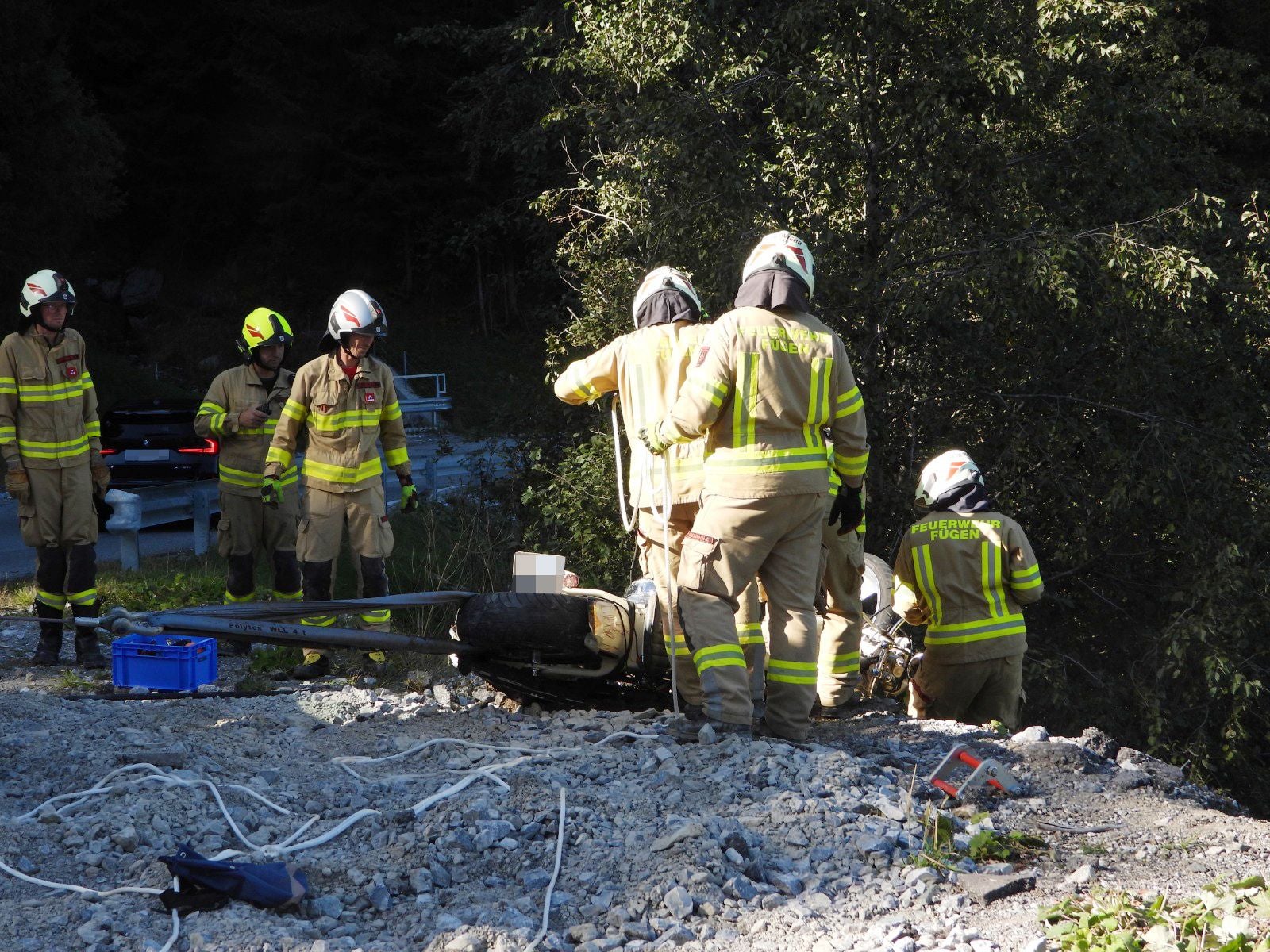 Feuerwehrleute bargen das Unfallfahrzeug am steinigen Abhang.