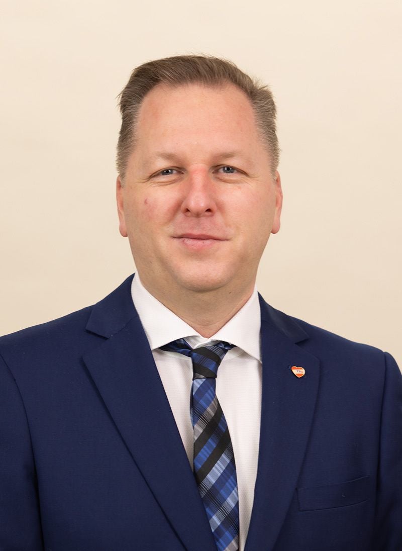 Mann im blauen Anzug und gestreifter Krawatte vor hellem Hintergrund.