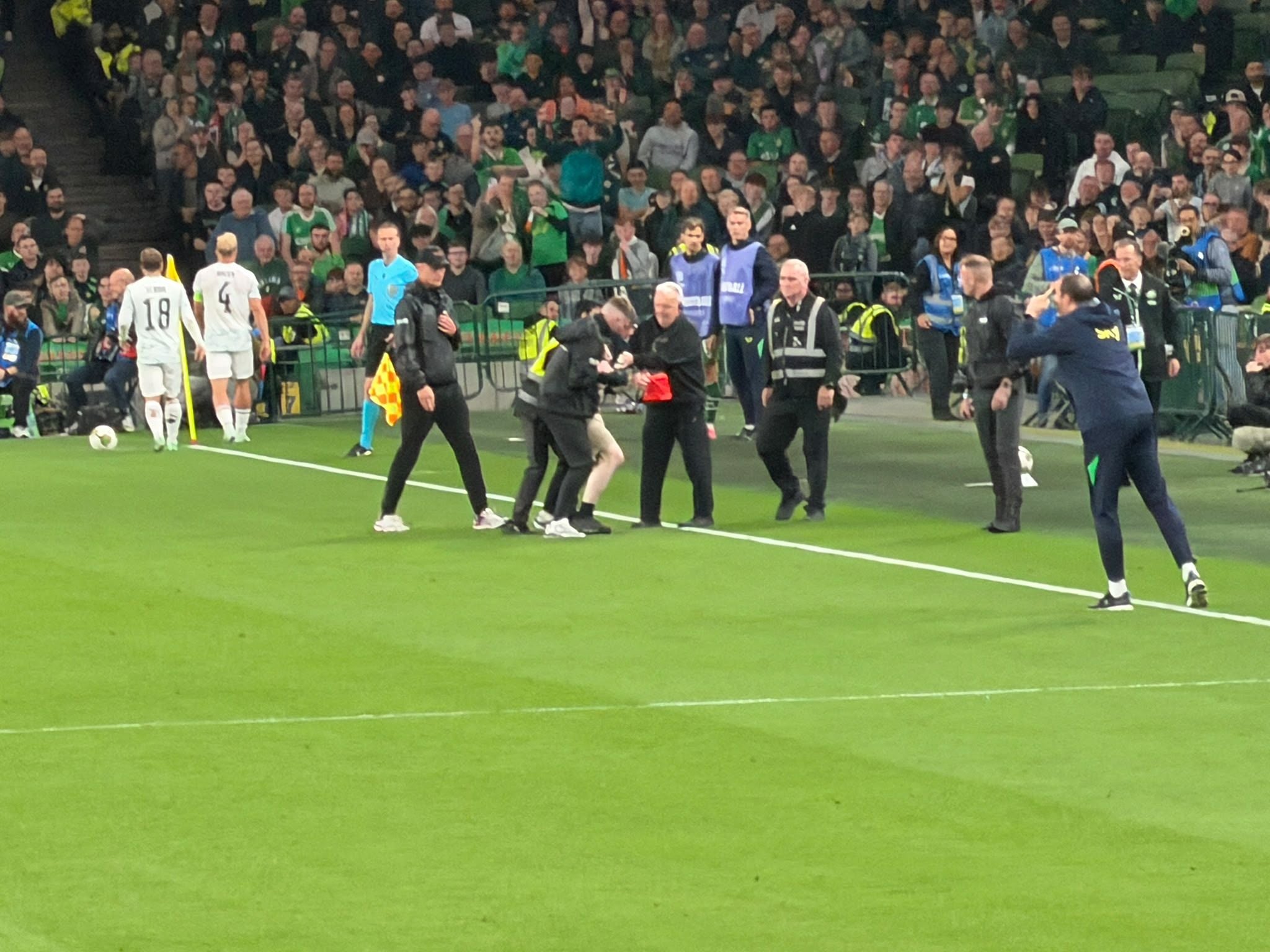 Ein Fußballspiel mit vielen Menschen am Spielfeldrand und Spielern auf dem Feld.