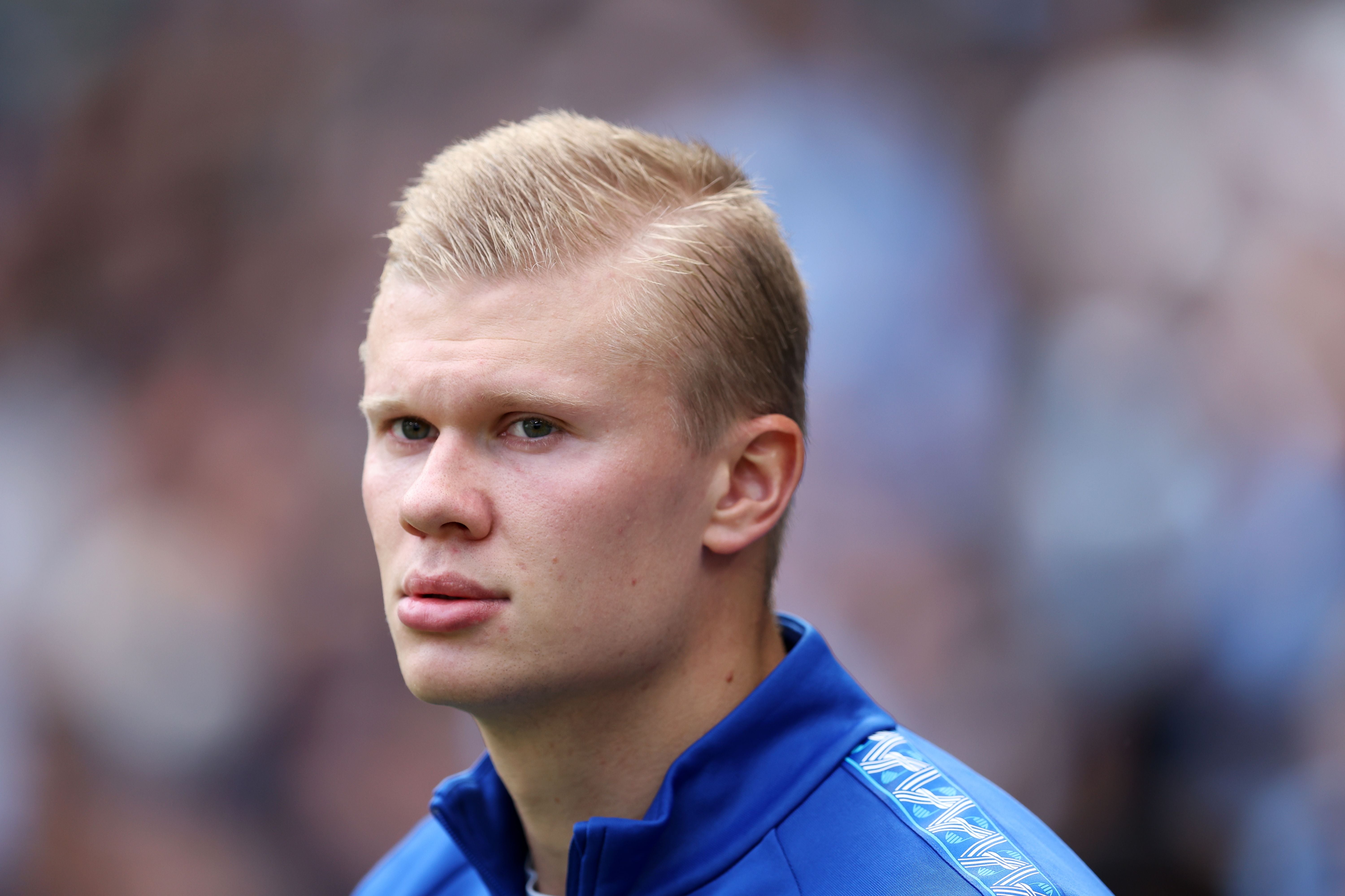 Ein junger Mann im blauen Trainingsanzug blickt ernst in die Kamera, unscharfer Hintergrund.