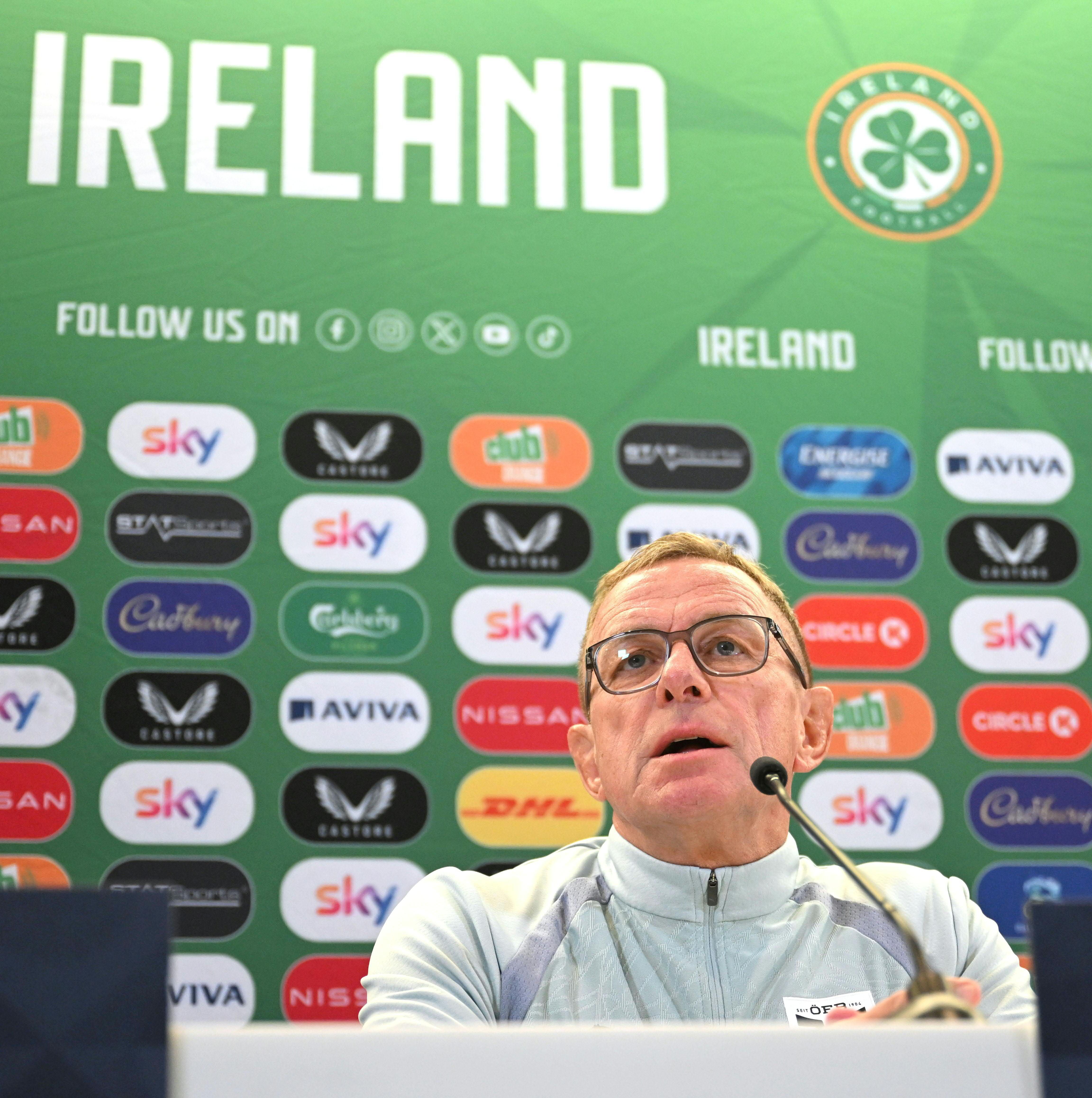 Ralf Rangnick bei einer Pressekonferenz vor grüner Irland-Wand mit Sponsorenlogos.