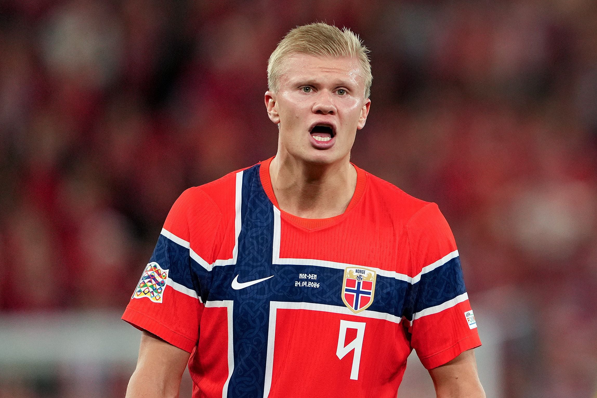 Ein norwegischer Fußballspieler im roten Trikot reagiert während eines Spiels im Stadion.
