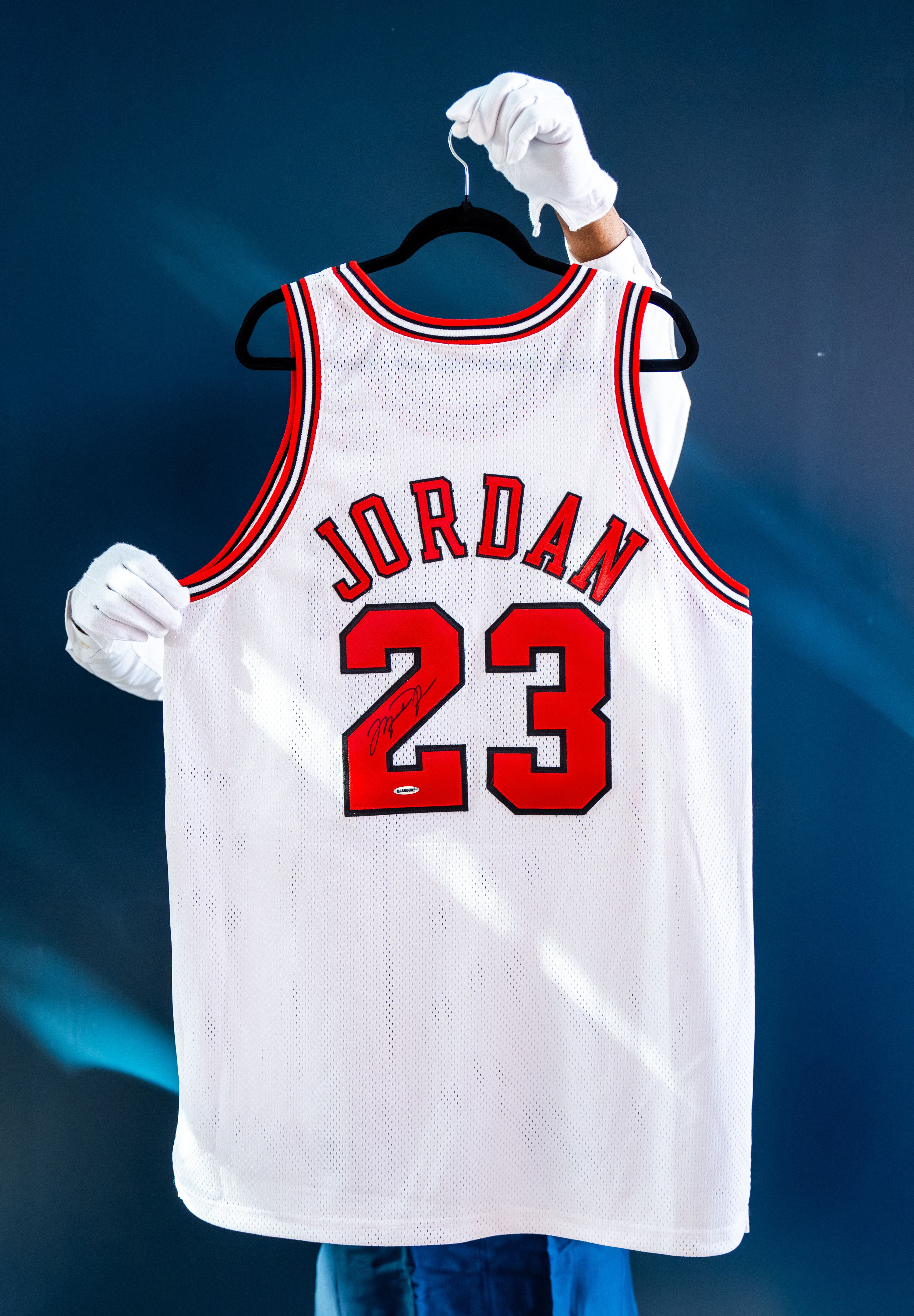 Jemand hält ein signiertes Michael-Jordan-Trikot mit der Nummer 23 auf einem Kleiderbügel.