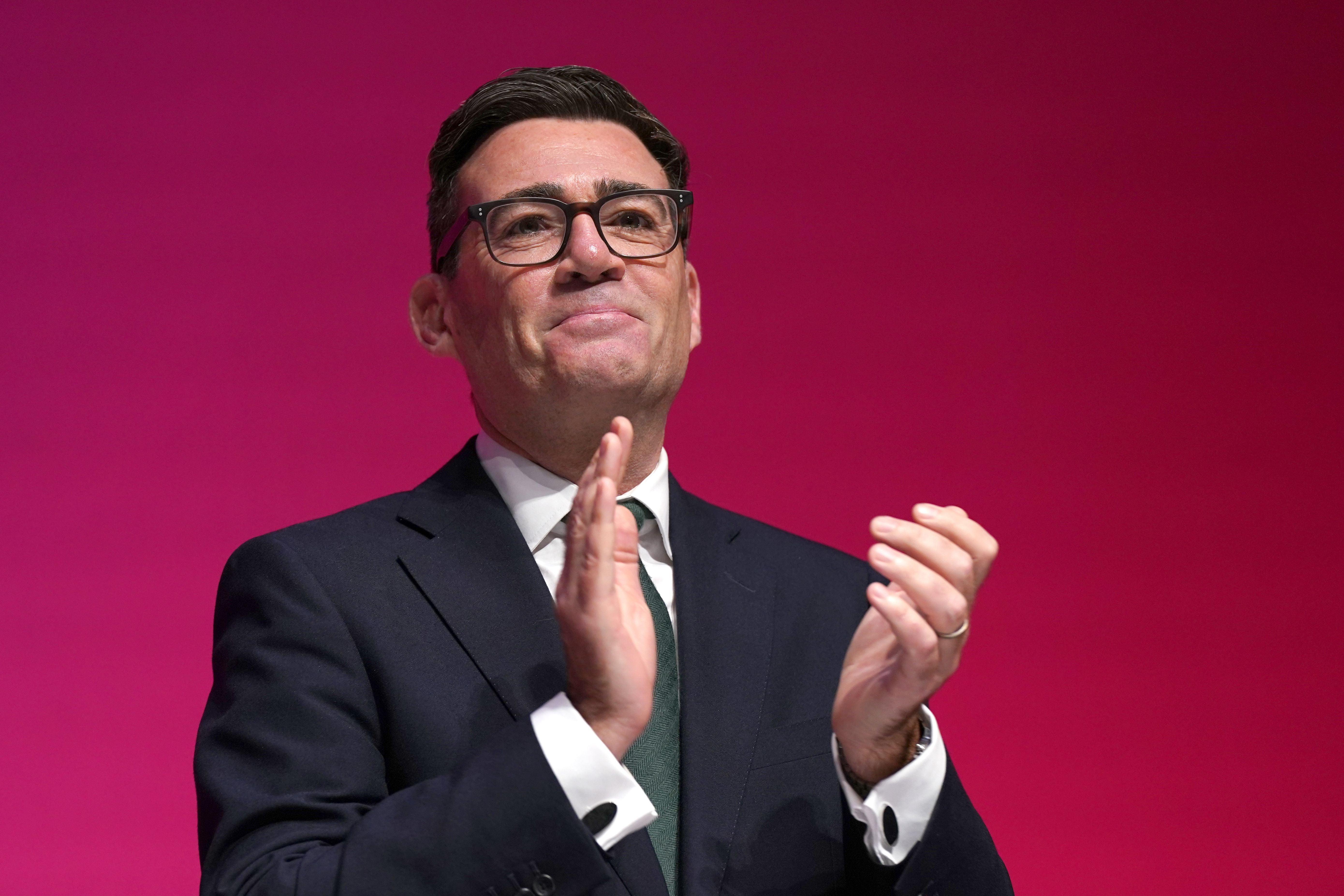 Ein Mann im Anzug klatscht vor einem pinken Hintergrund und schaut nach vorne.