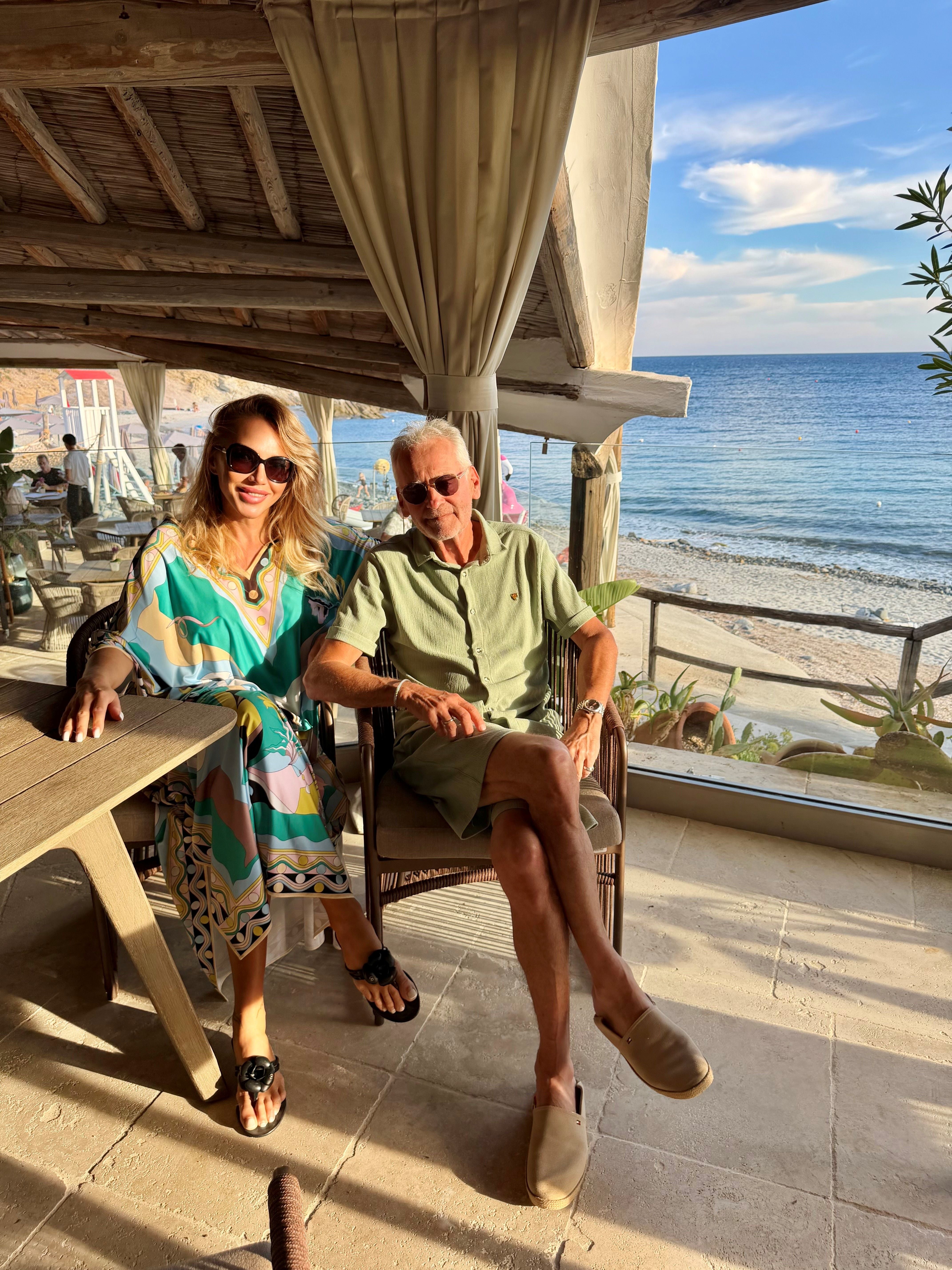 Ein Mann und eine Frau sitzen entspannt in einem Strandrestaurant mit Blick aufs Meer.