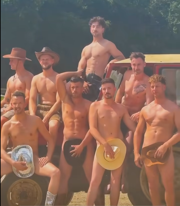 Gruppe junger Männer posiert nackt mit Hüten vor einem Traktor auf dem Land.