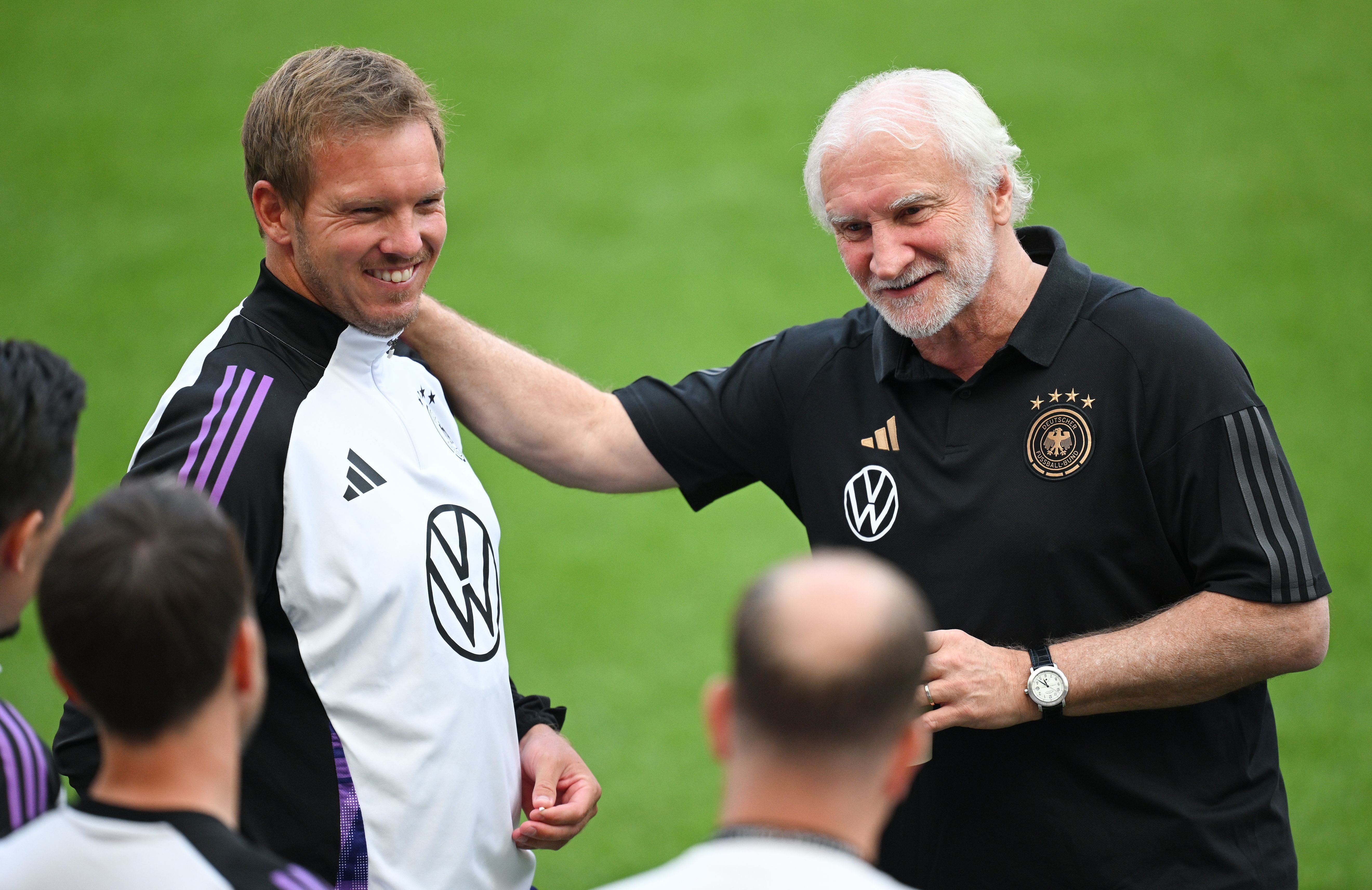 Zwei Männer im Trainingsanzug lachen auf einem Fußballfeld während einer Trainingseinheit.