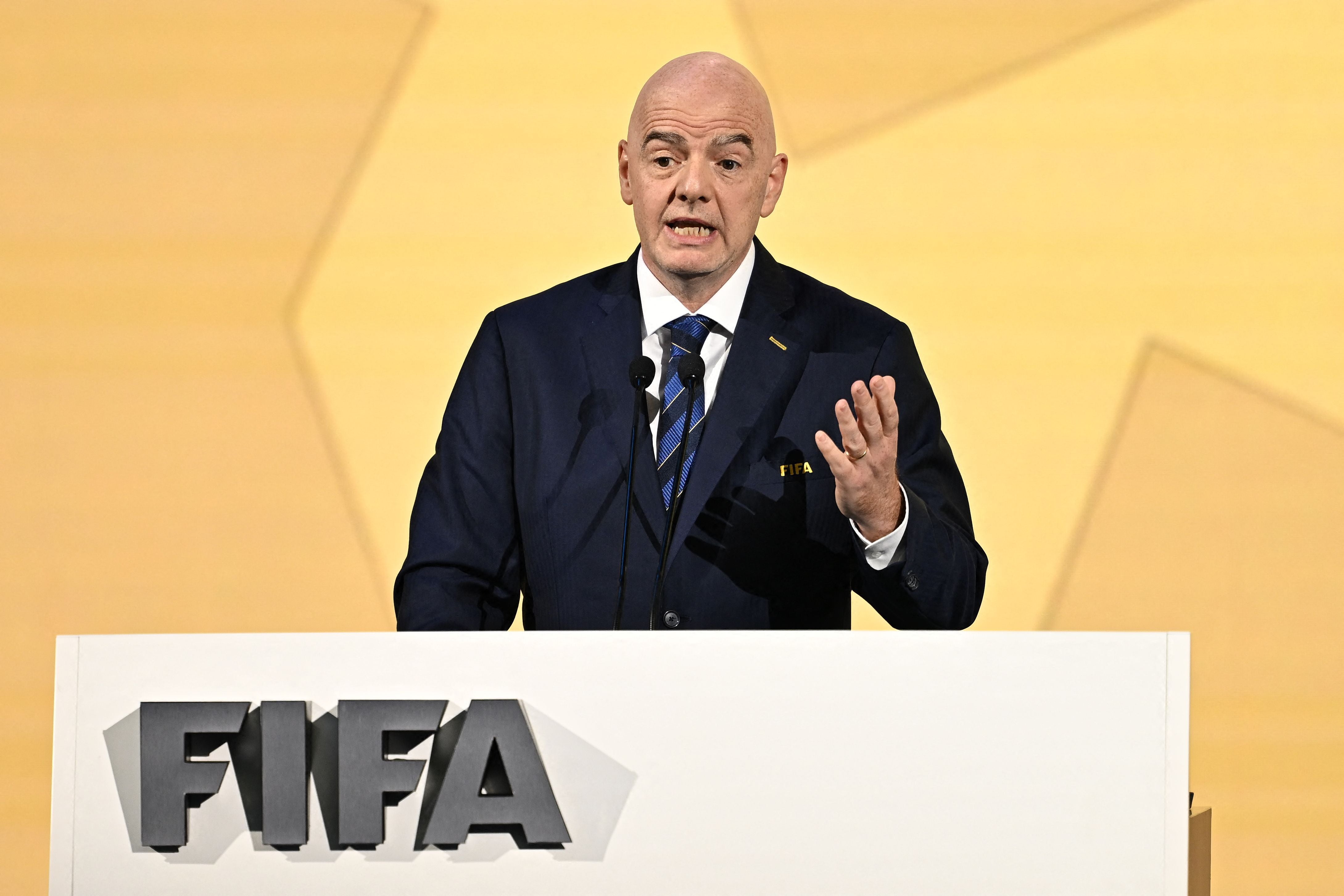Ein Mann im Anzug spricht bei einem FIFA-Kongress an einem Podium mit FIFA-Logo.