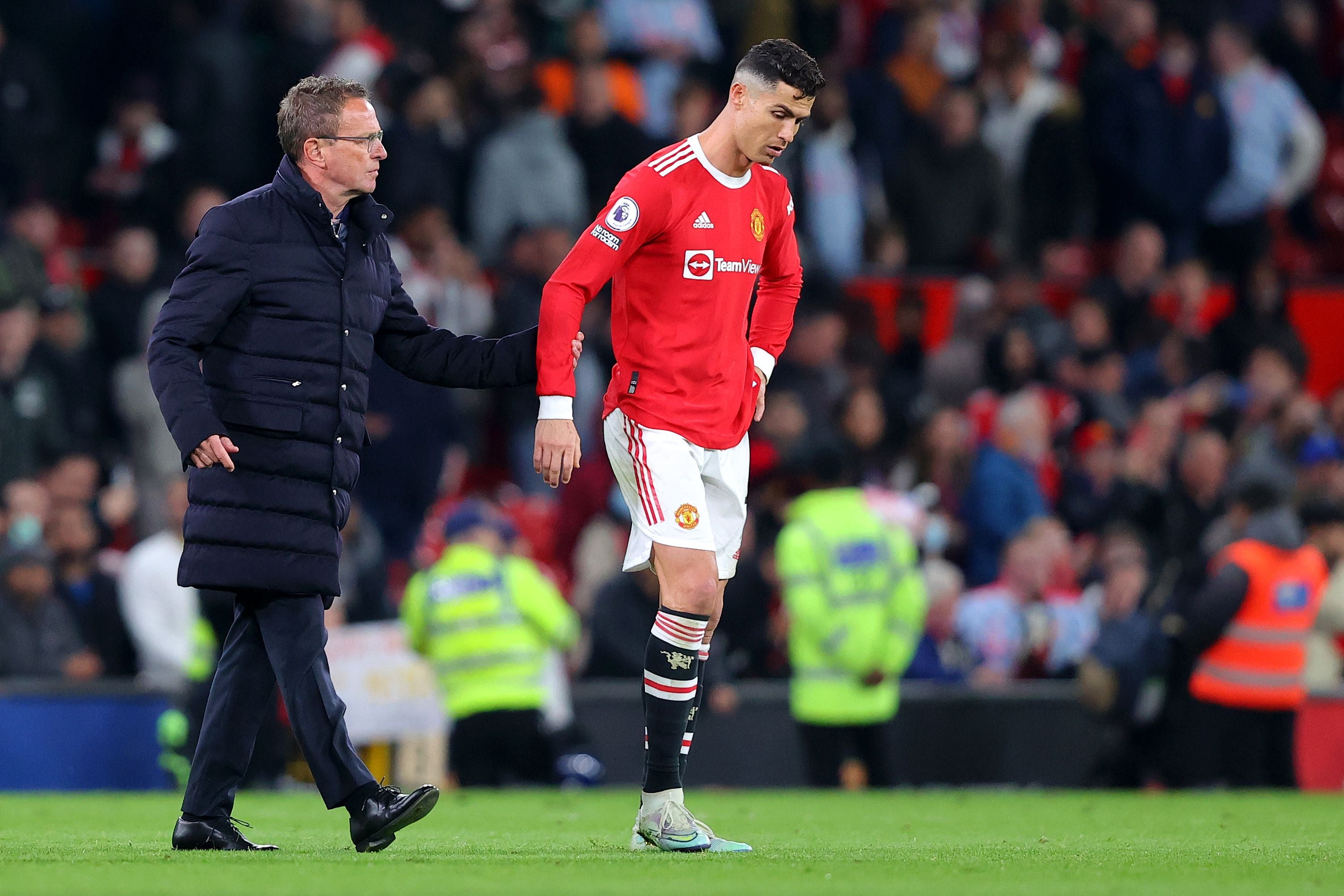 Ein Trainer tröstet einen enttäuschten Fußballspieler von Manchester United auf dem Spielfeld.