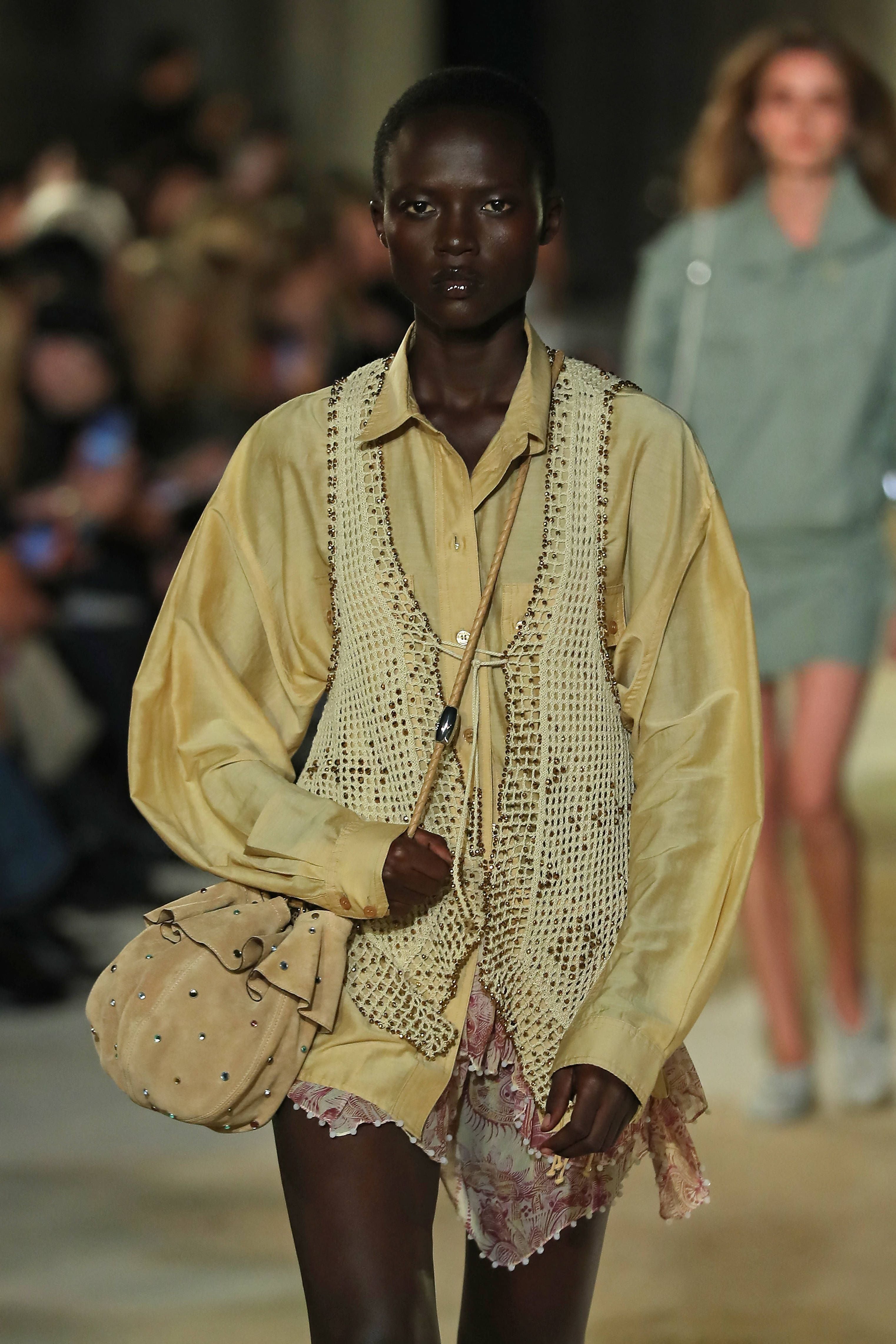 Model trägt beigefarbene Bluse, gehäkelte Weste und Shorts auf dem Laufsteg bei der Paris Fashion Week.