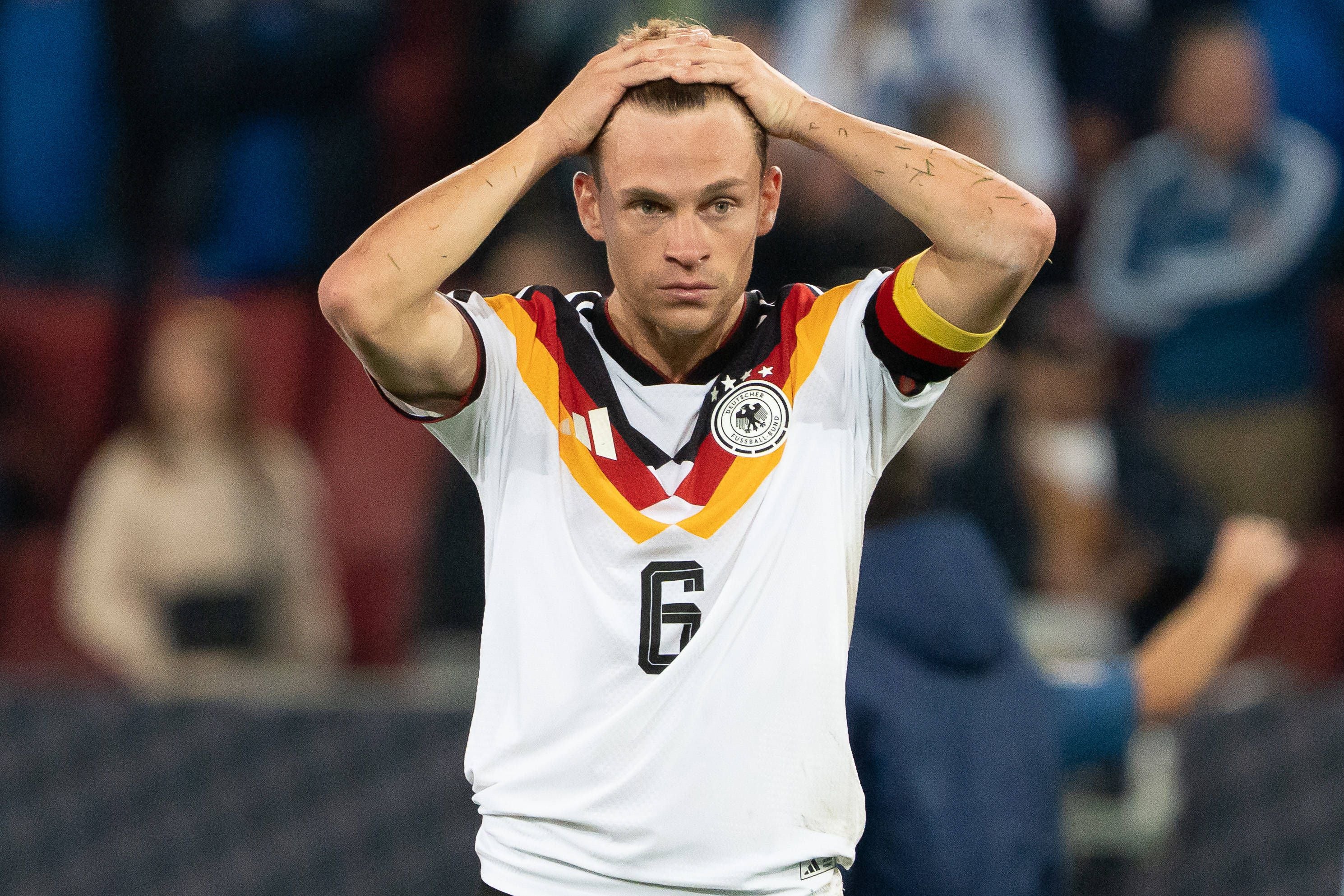 Ein deutscher Fußballspieler hält enttäuscht beide Hände auf dem Kopf nach einer Niederlage.