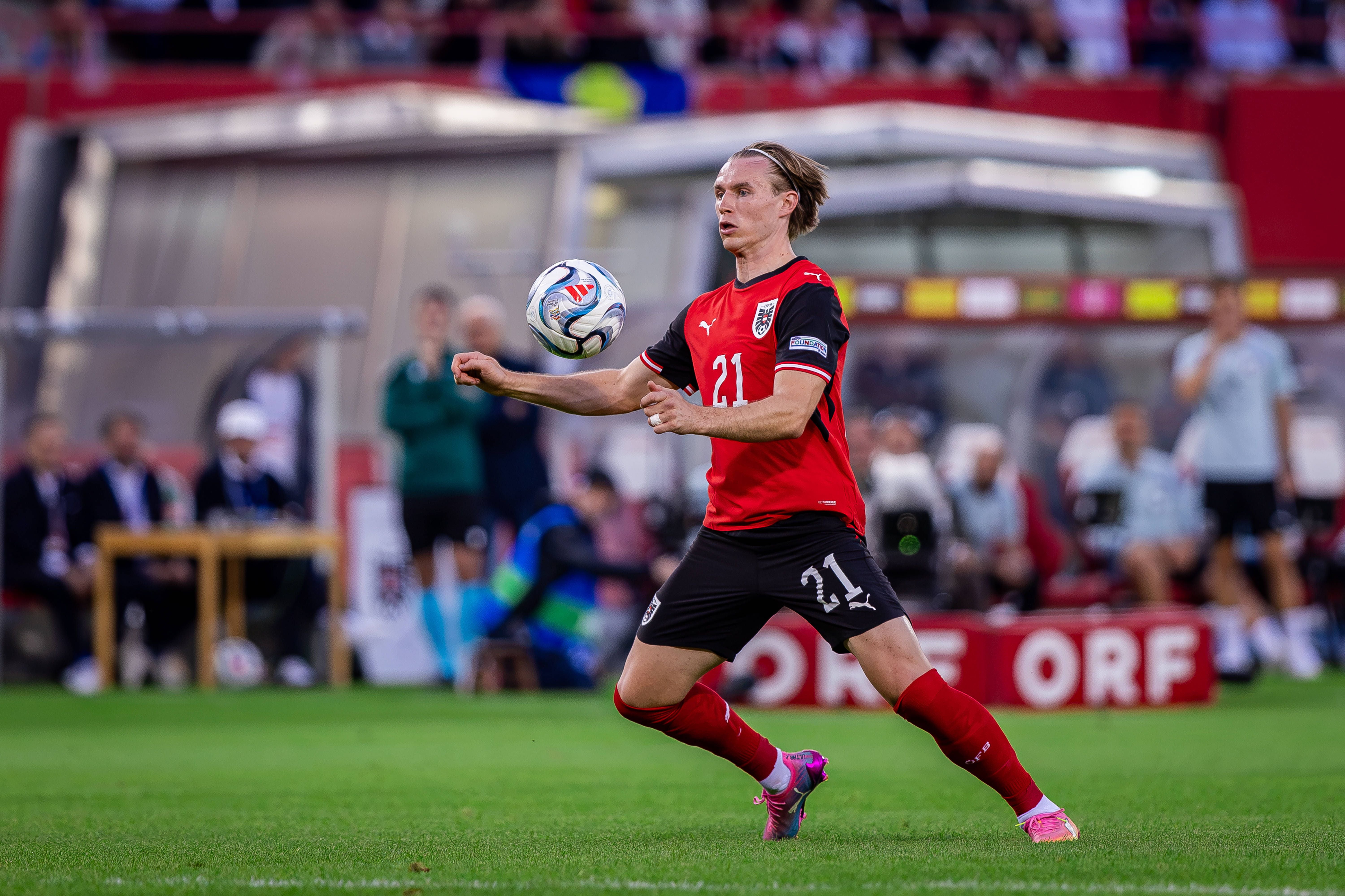 Patrick Wimmer kontrolliert im rot-schwarzen ÖFB-Trikot mit der Rückennummer 21 konzentriert den Ball auf dem Spielfeld.