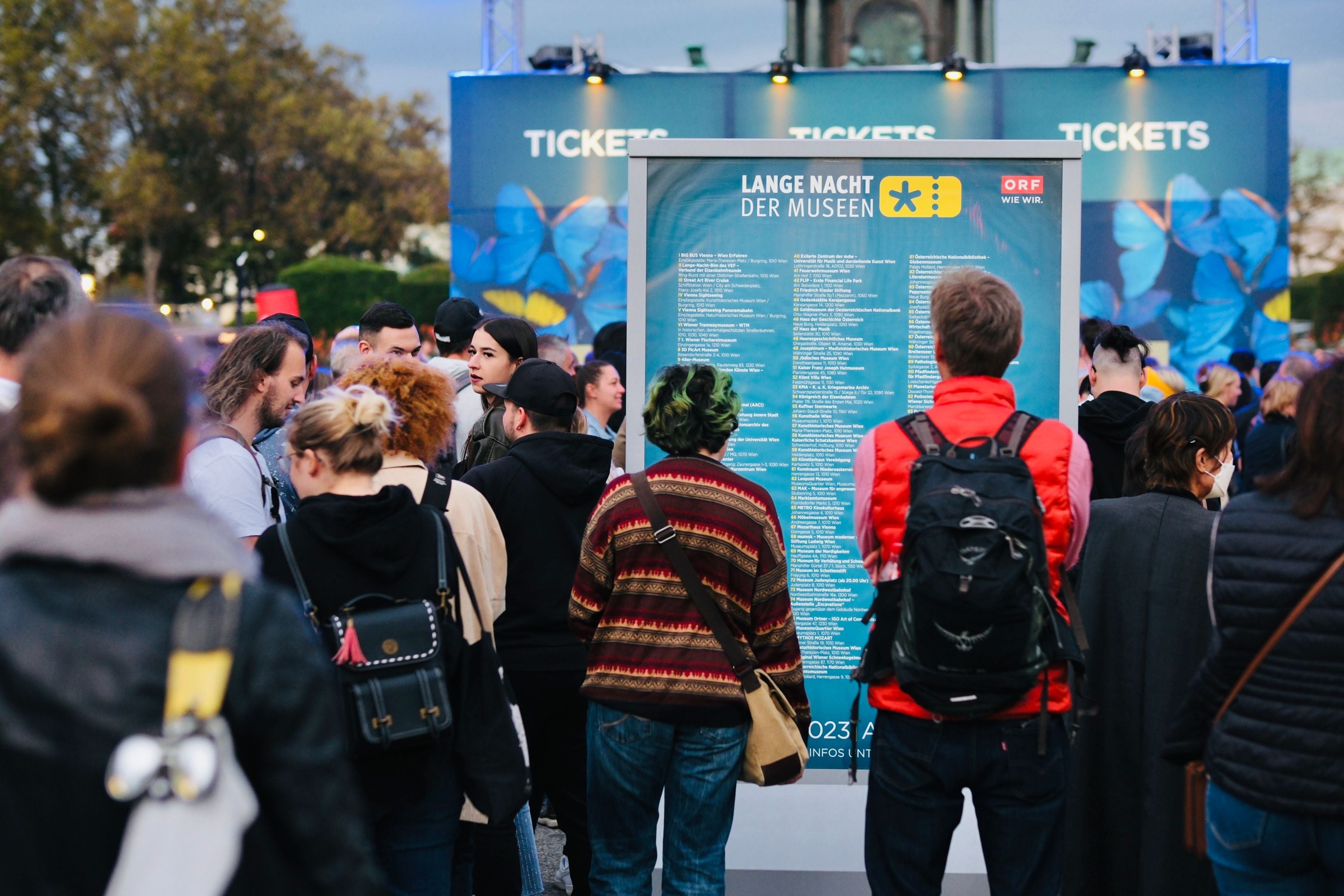 Viele Menschen stehen vor einer Infotafel zur "Langen Nacht der Museen" im Freien.