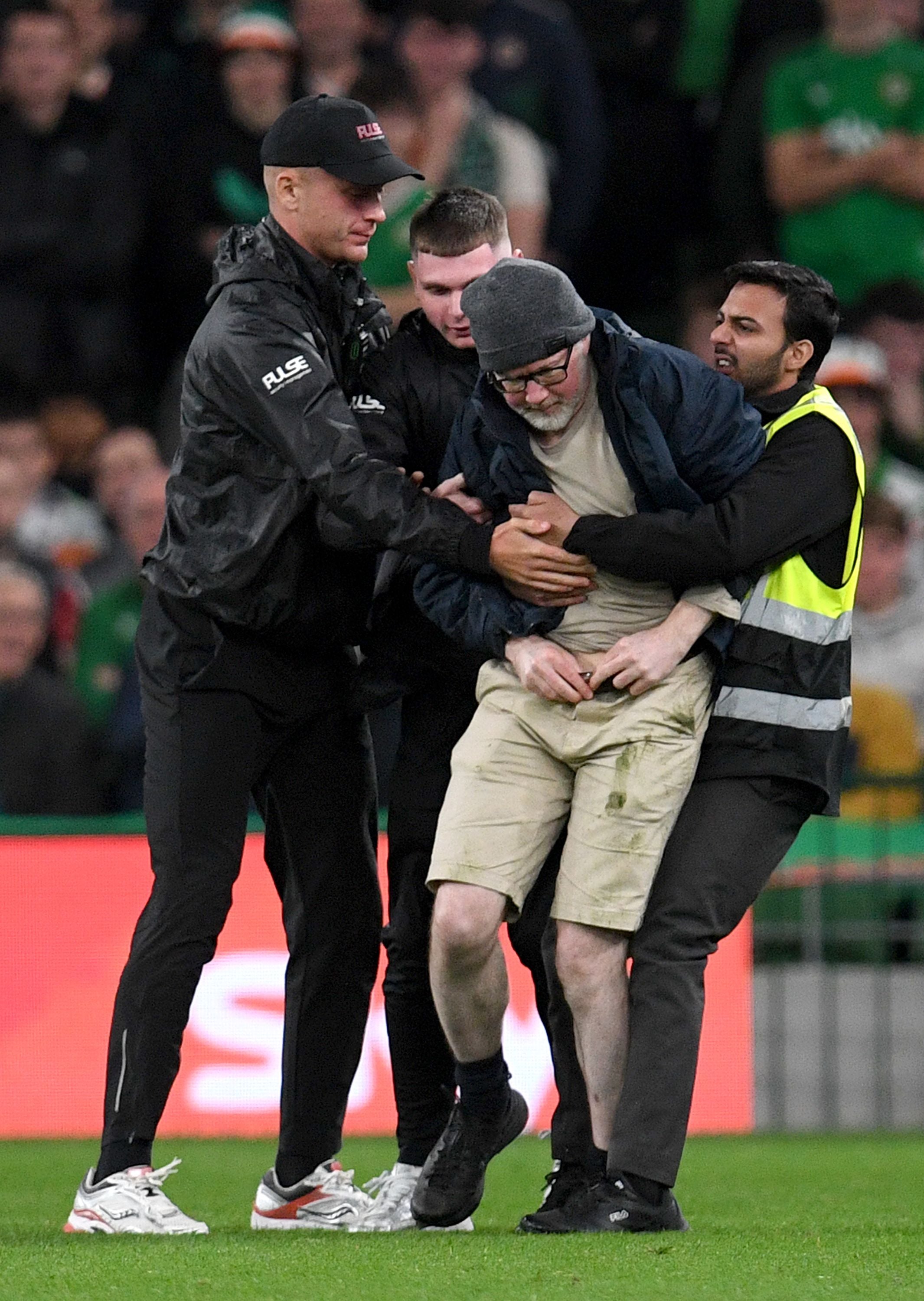 Sicherheitskräfte halten einen Flitzer während eines Fußballspiels im Stadion fest.