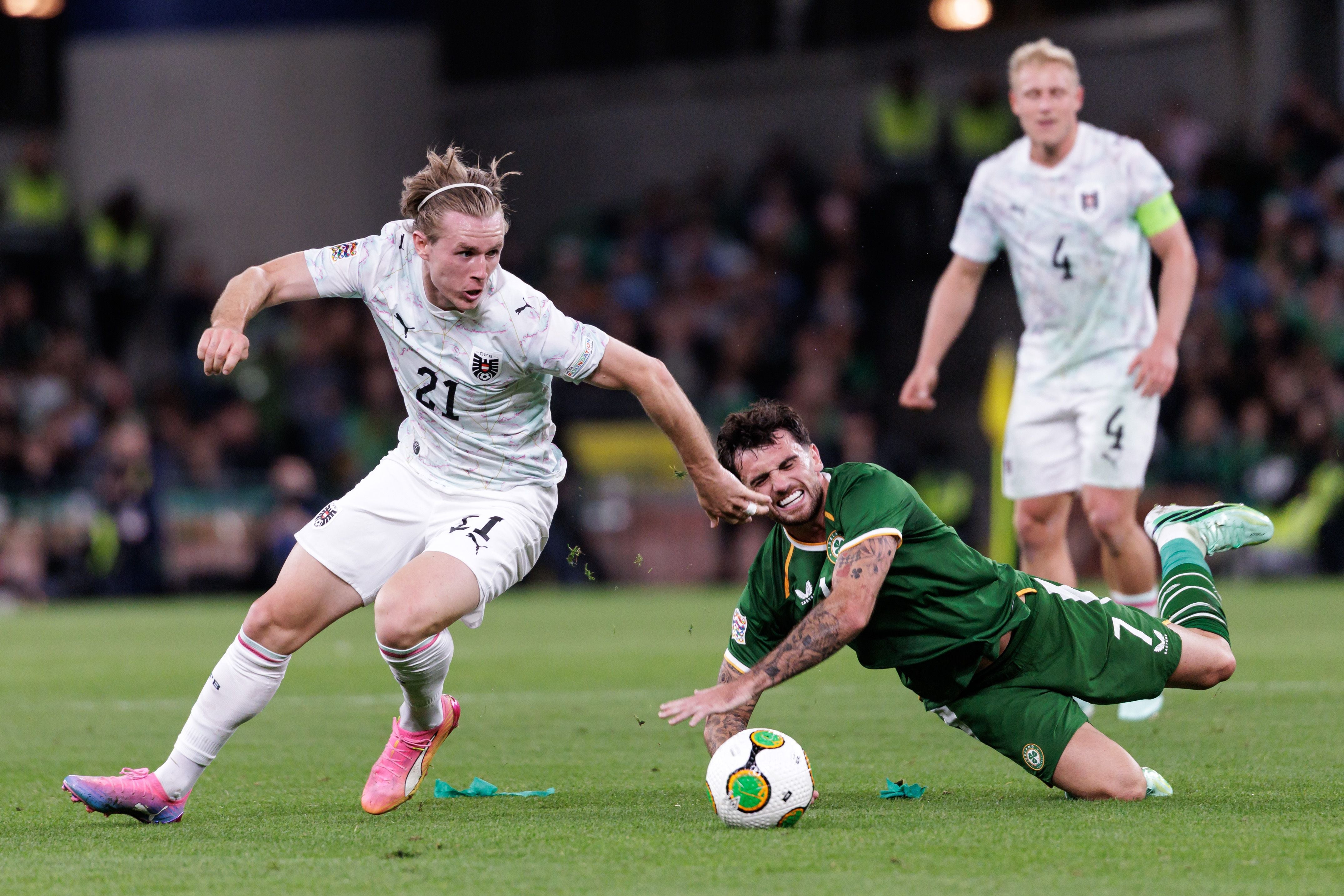 Ein österreichischer und ein irischer Fußballspieler kämpfen um den Ball, einer fällt zu Boden.