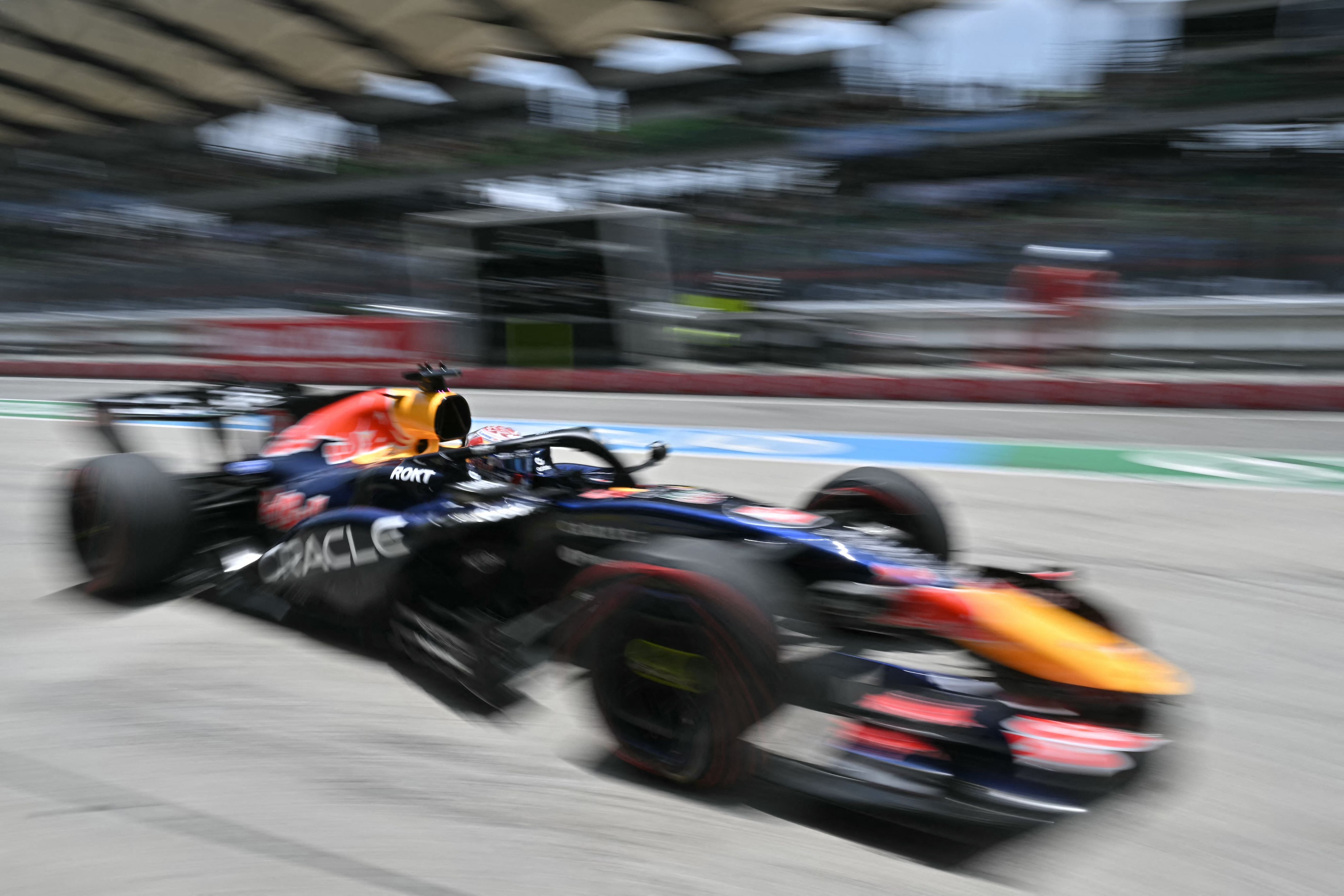 Ein Red Bull Rennwagen fährt mit hoher Geschwindigkeit durch die Boxengasse auf einer Rennstrecke.